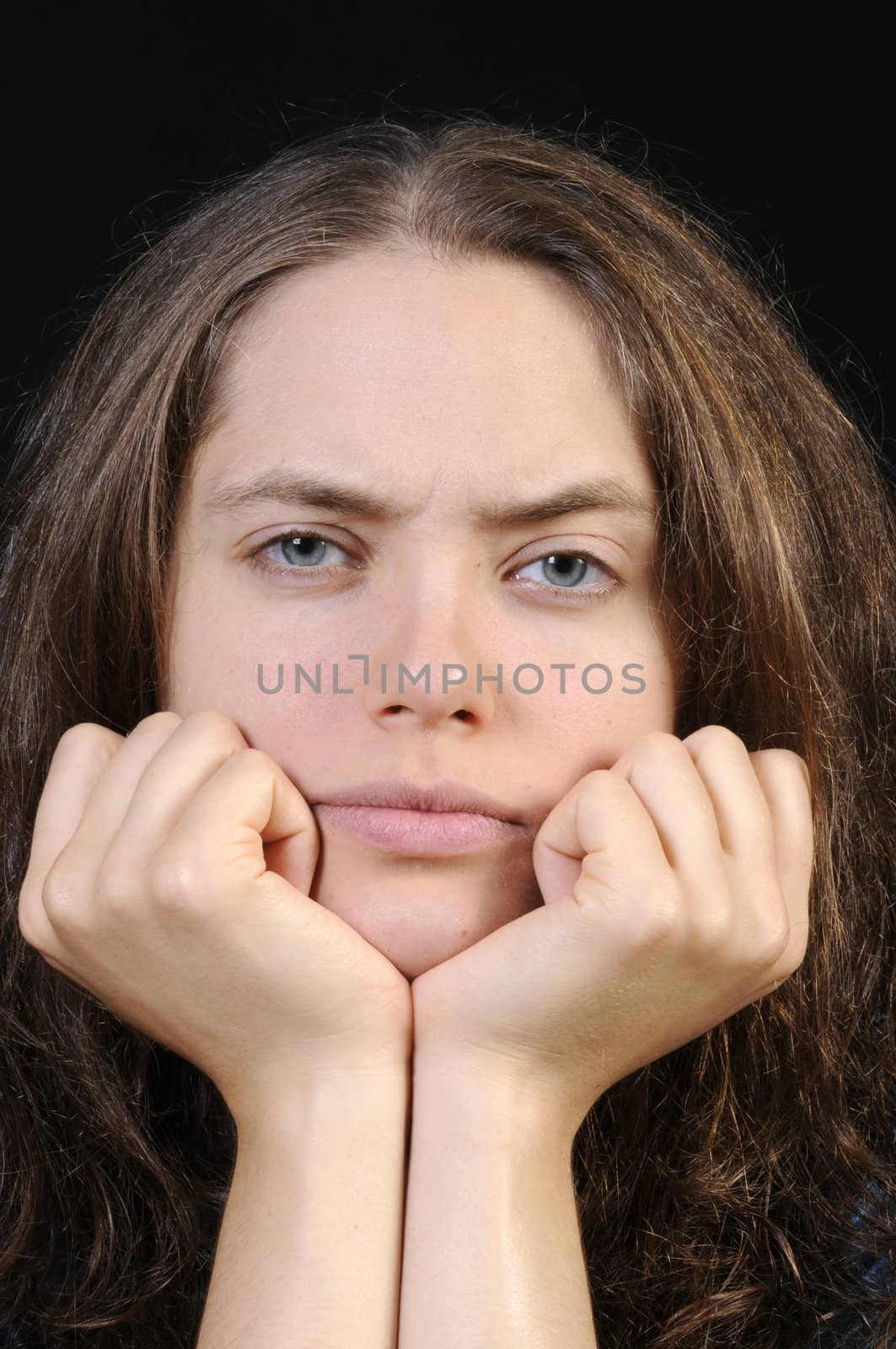 Beautiful young brunette woman in closeup with head rested in hands 