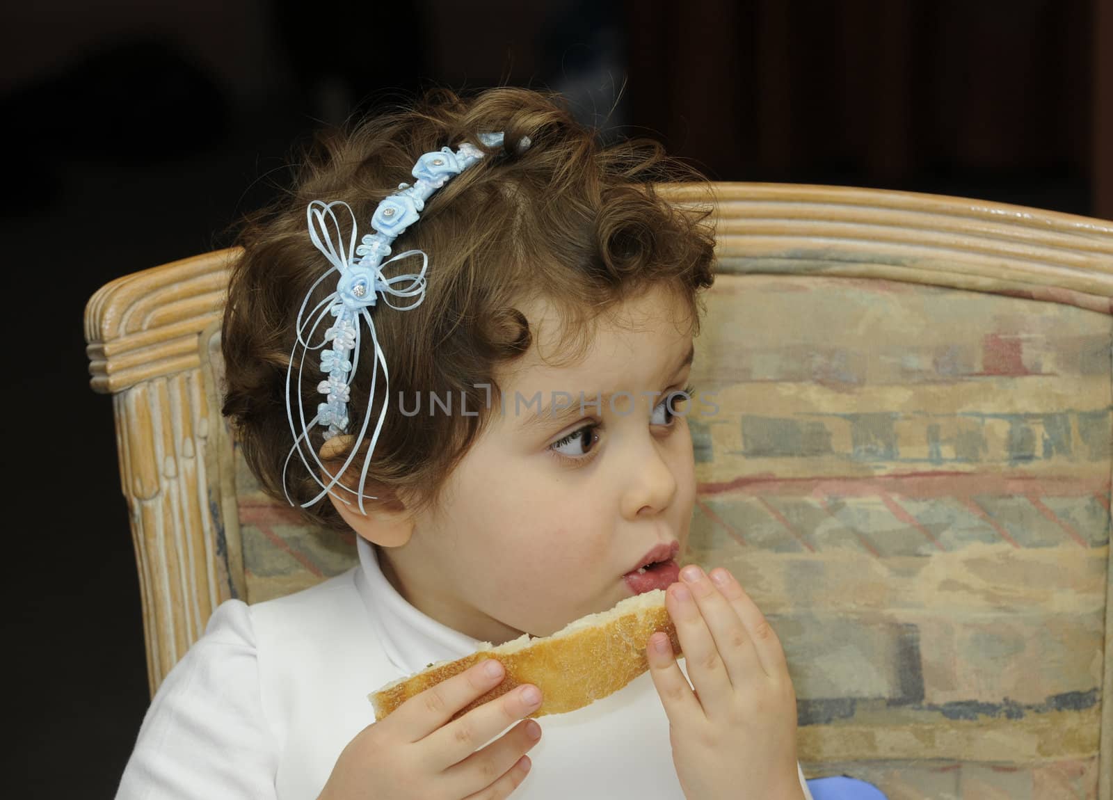 smiling young flower girl at a wedding eating some bread