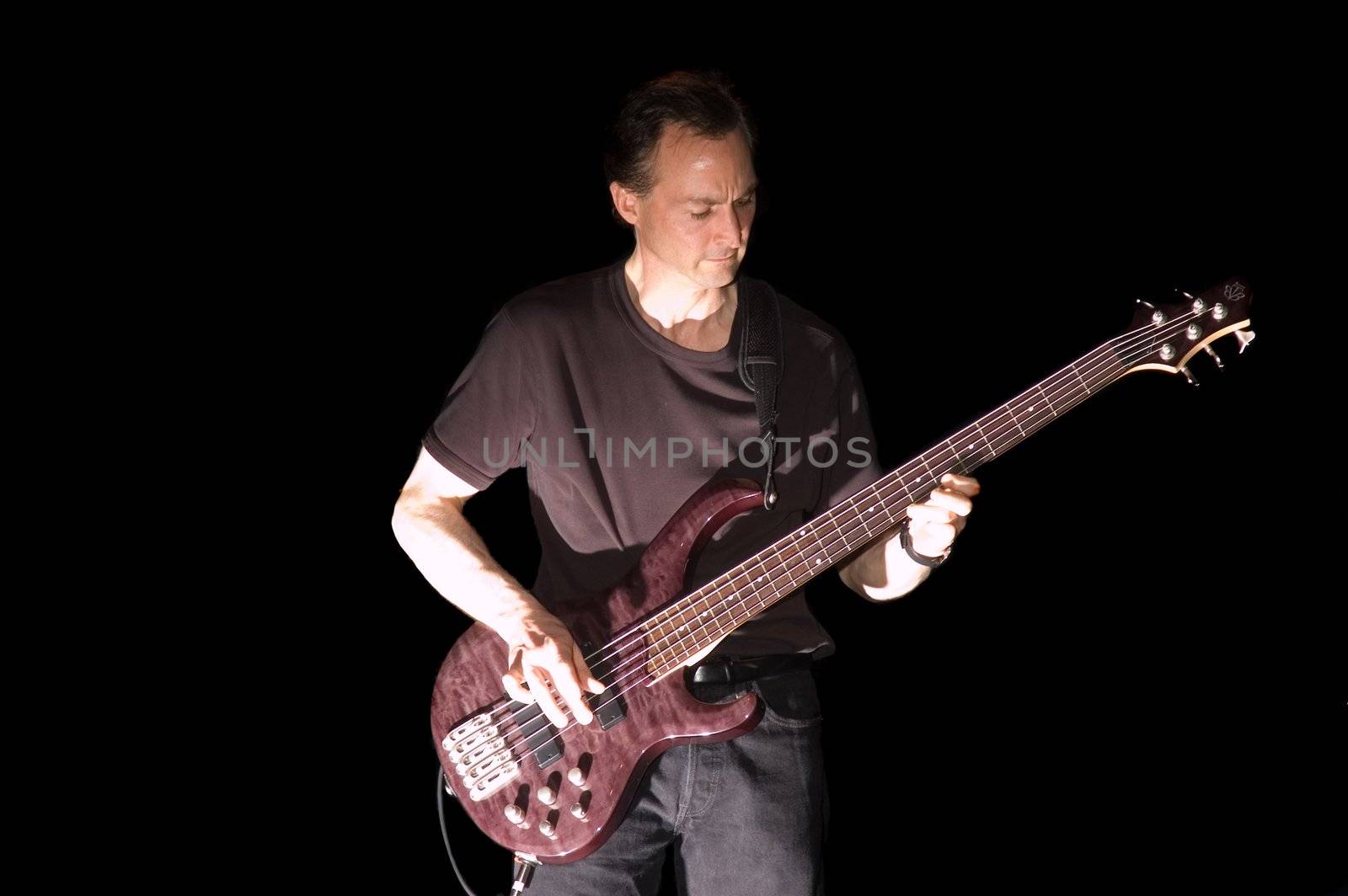 Bass Guitarist playing while isolated on black during live concert