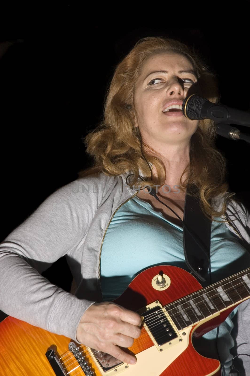 female singer/Guitarist playing while isolated on black during live concert