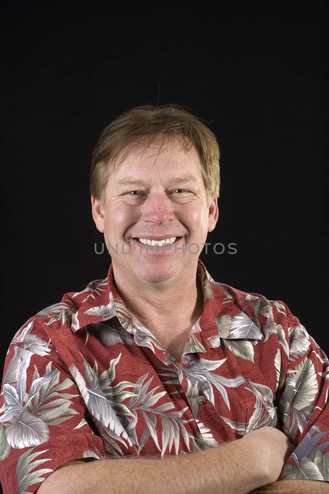 Happy smiling casual businessman in a floral Hawaiin style shirt over a black background
