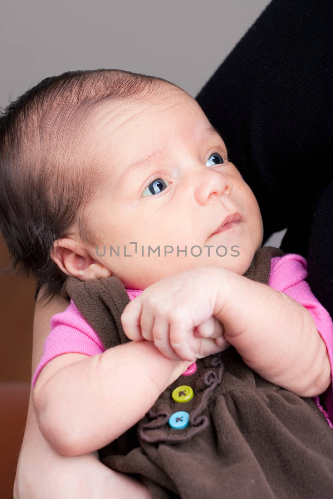 A newborn baby being held in the arms of her mother.