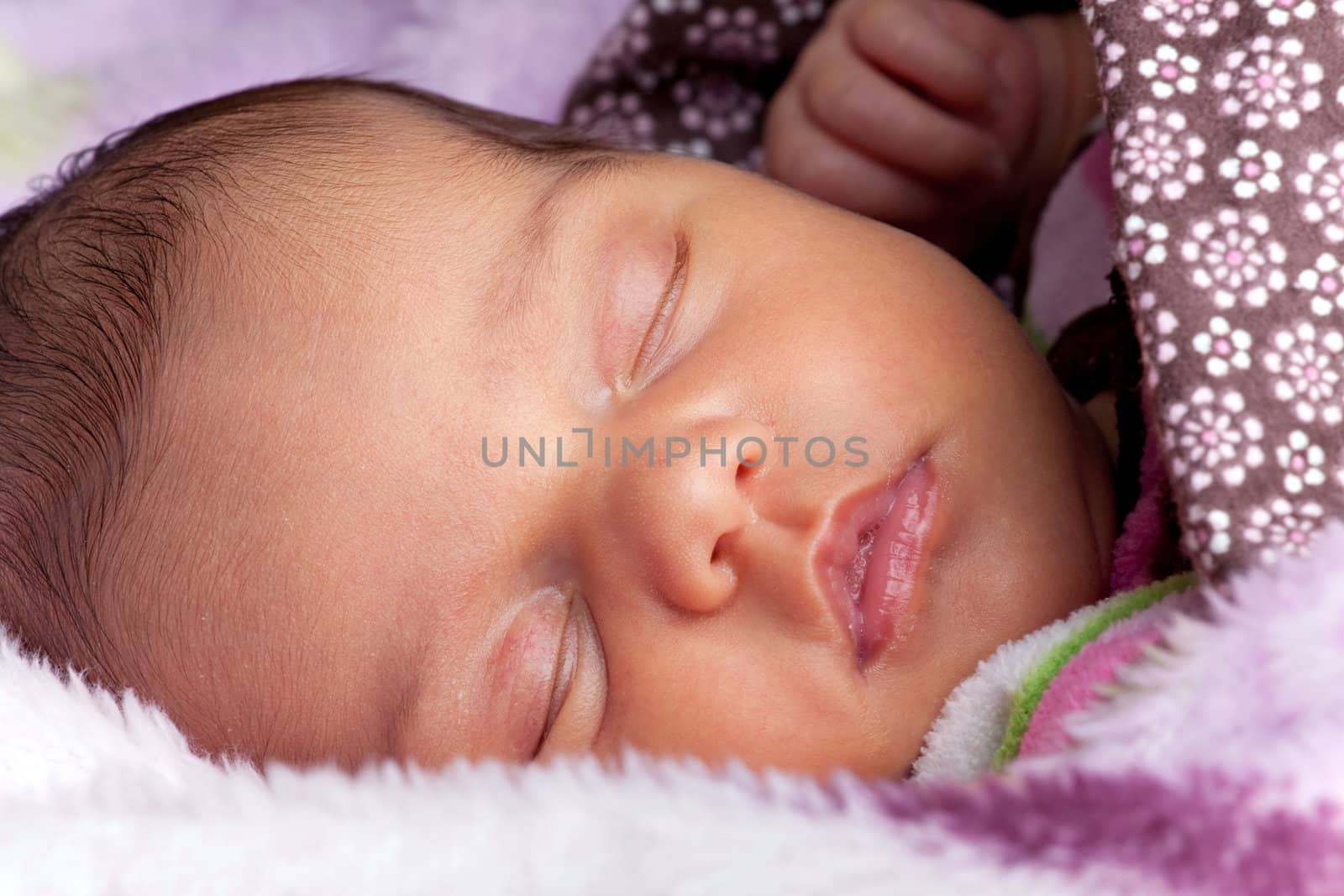 A newborn baby sleeping peacefully under blankets.