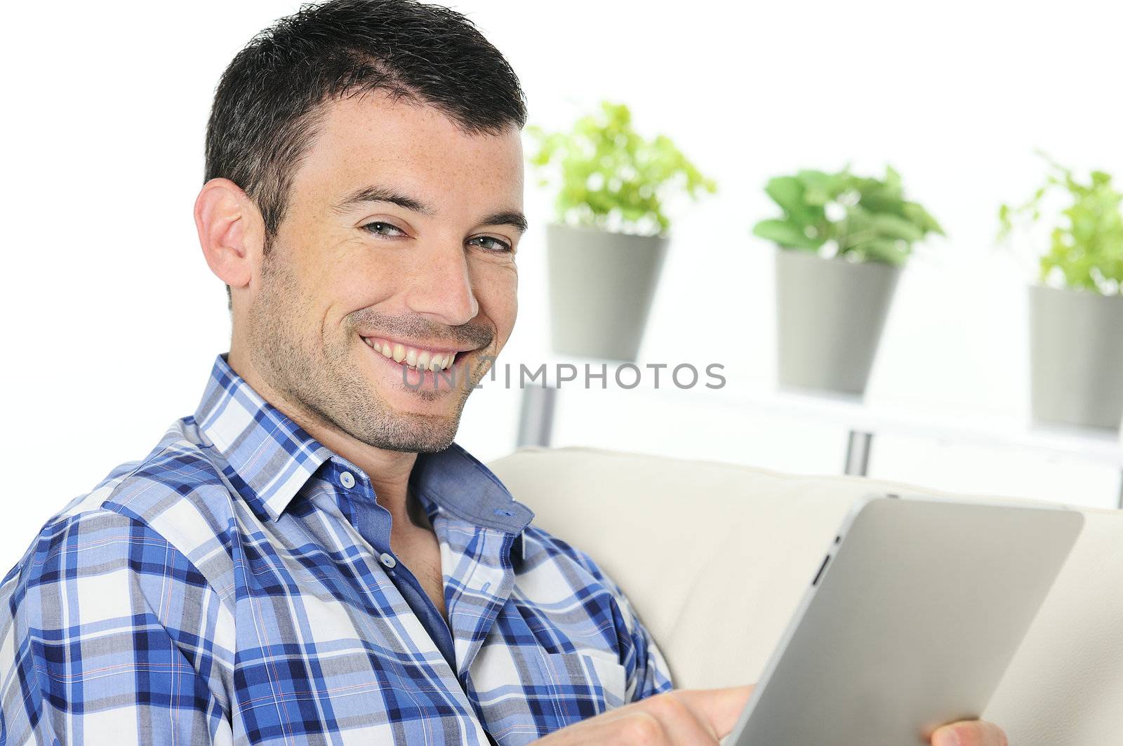 attractive relaxed and positive man is surfing on his tablet