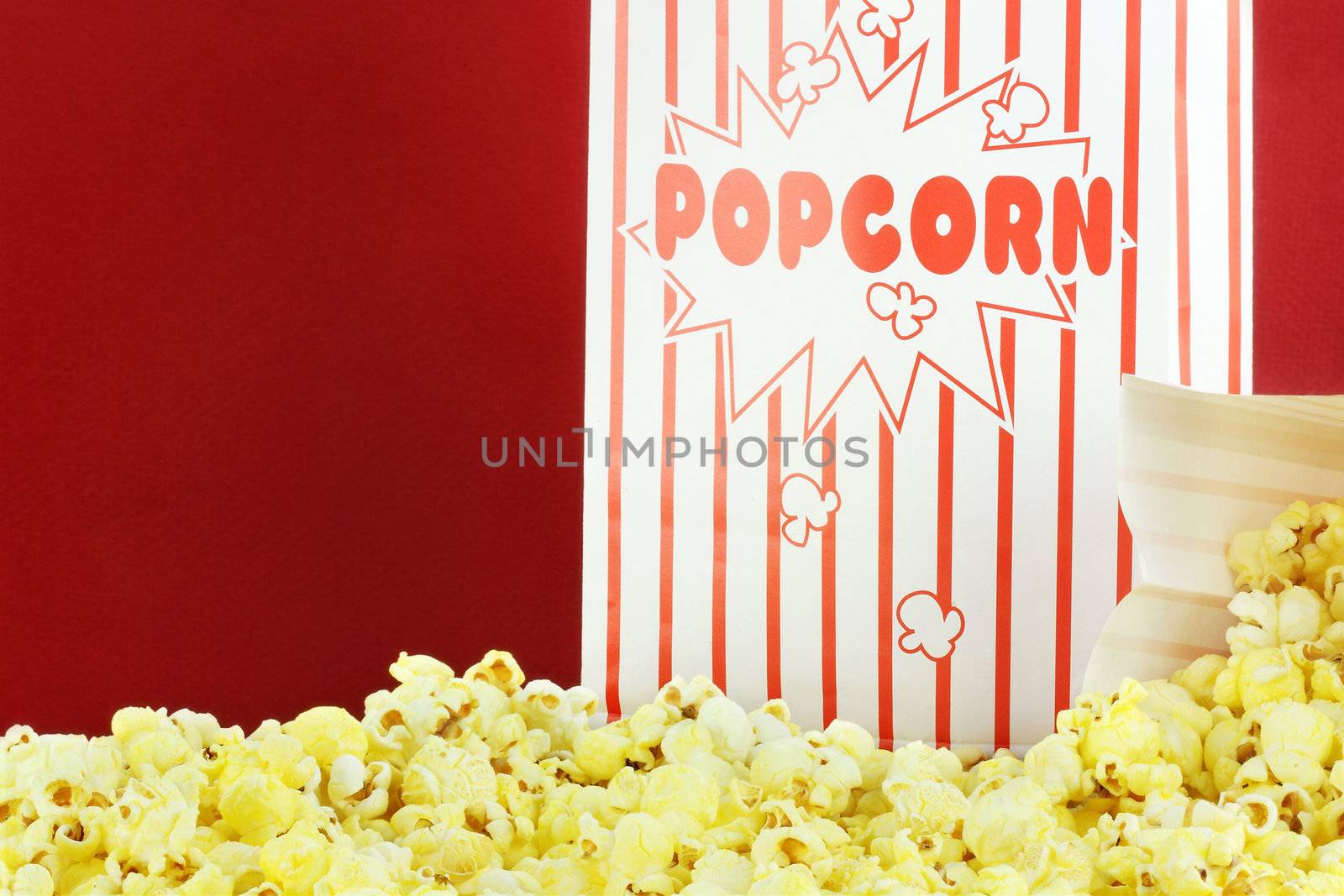 Bags of buttery popcorn against a red background. Room for text.

