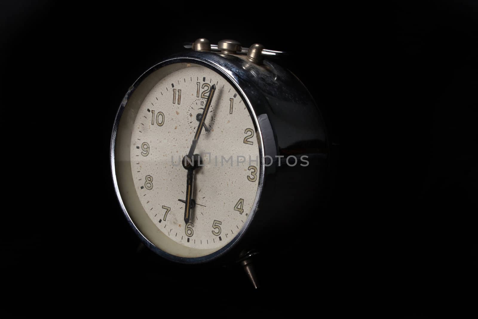 An old alarm clock, on black studio background.