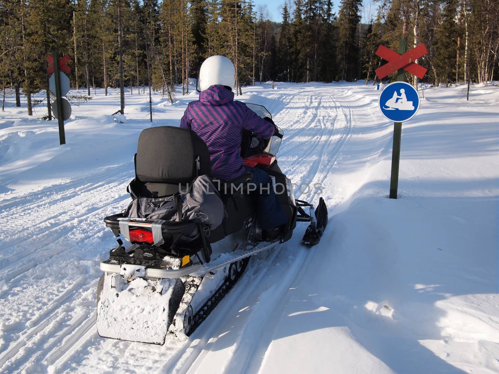 Person on a snow mobile on a track with a snow mobile traffic sign.