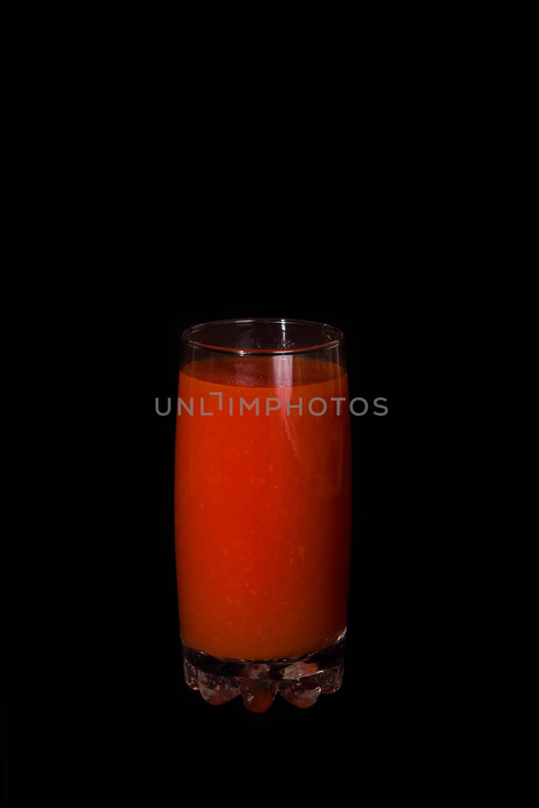 Glass of tomato juice on a black background