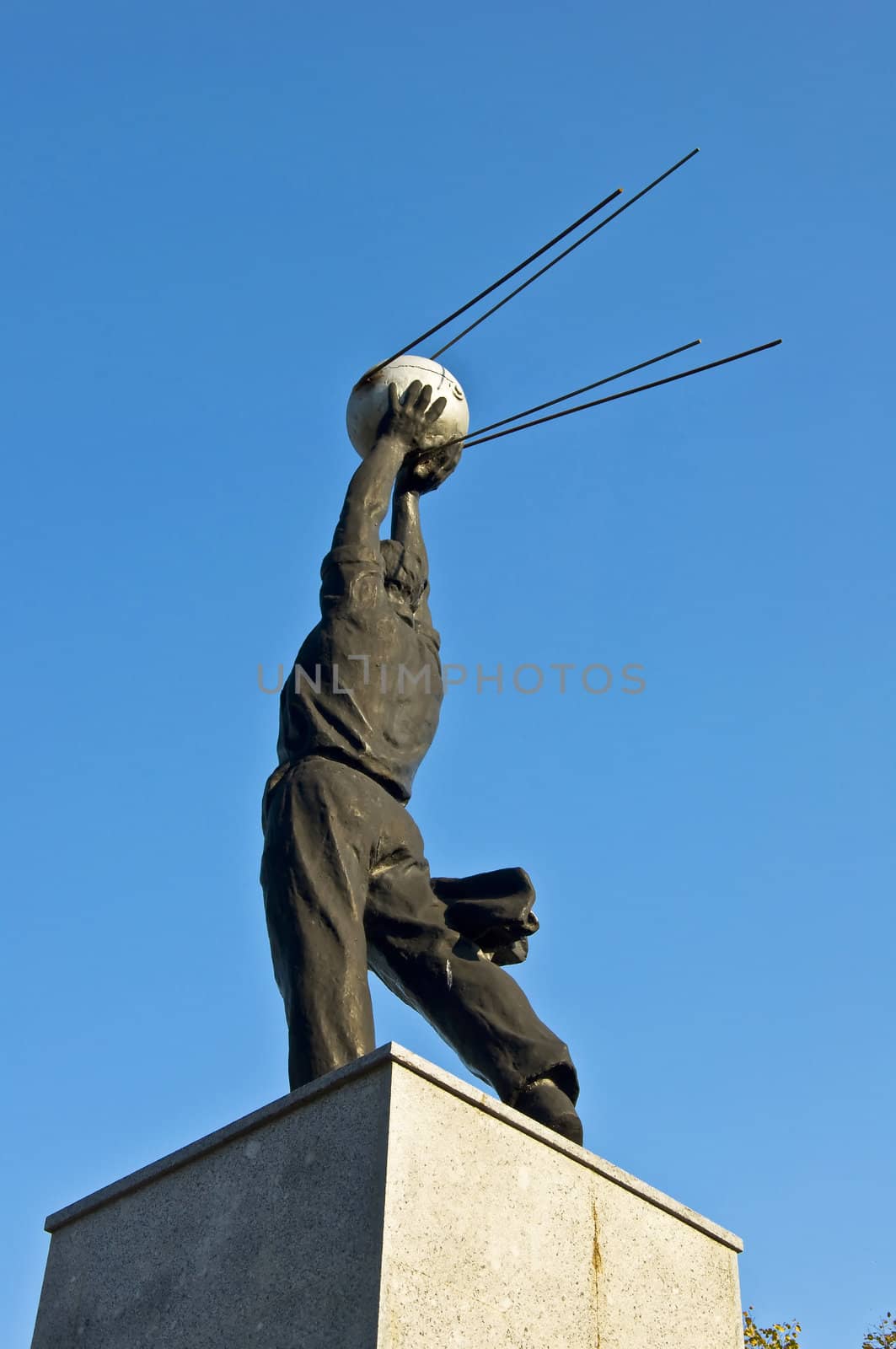 Monument of the first satellite of the Earth. A man holds a satellite in the blue clear sky.