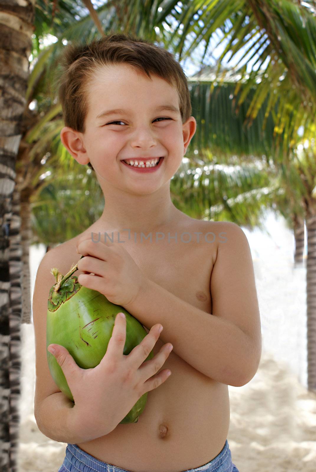 A five Years old holding a coconut, happy in a tropical place.