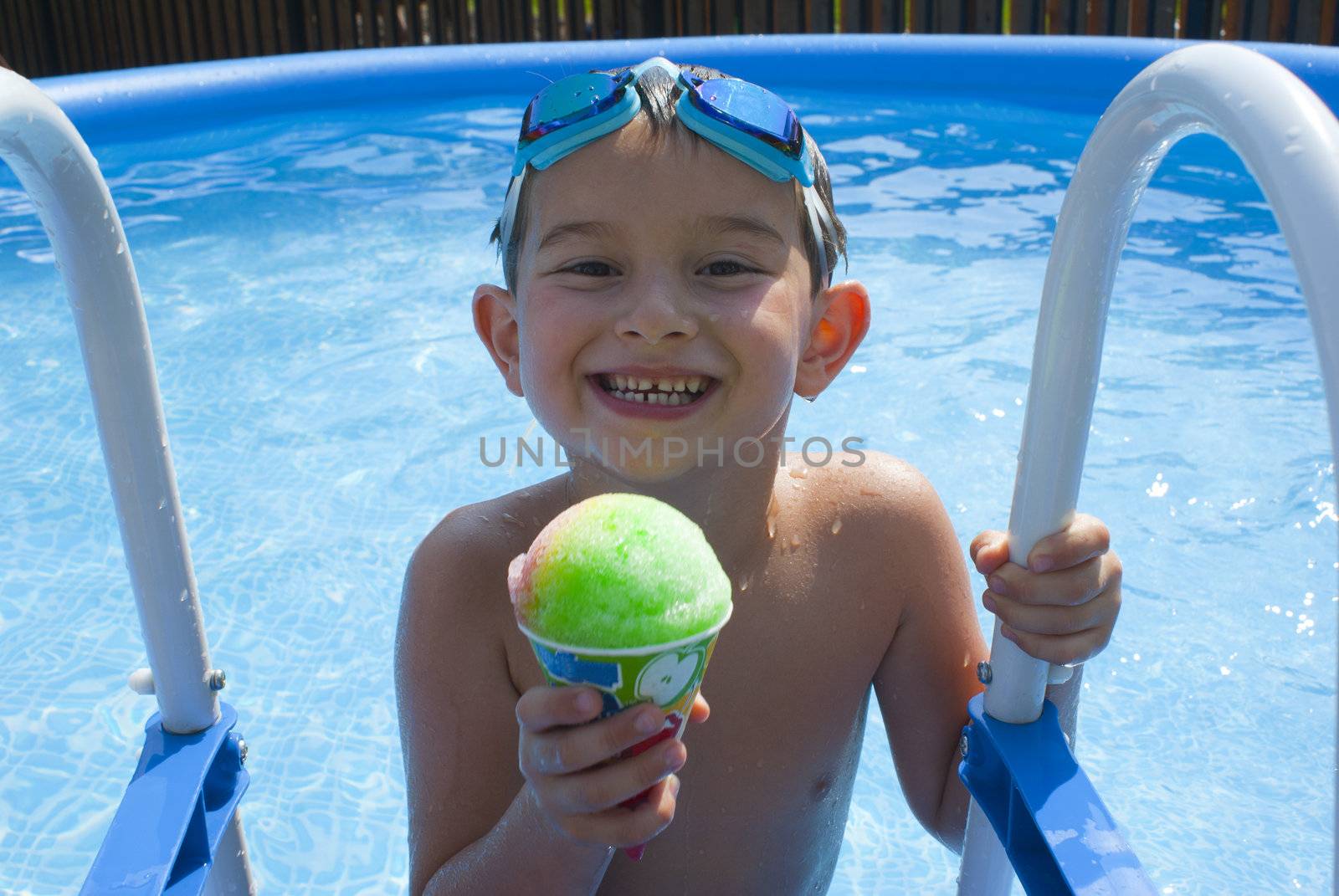 Six Years old kid having an Ice Cone in a swimming pool to cool down.