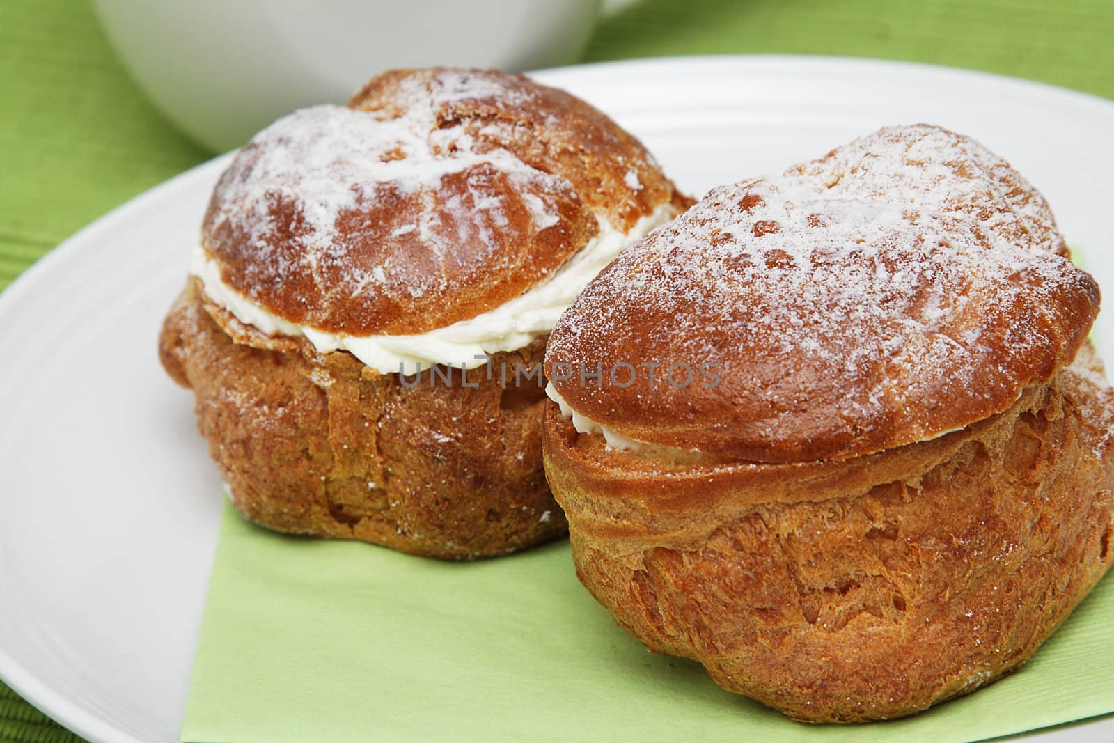 Two profiteroles on white plate with green napkin