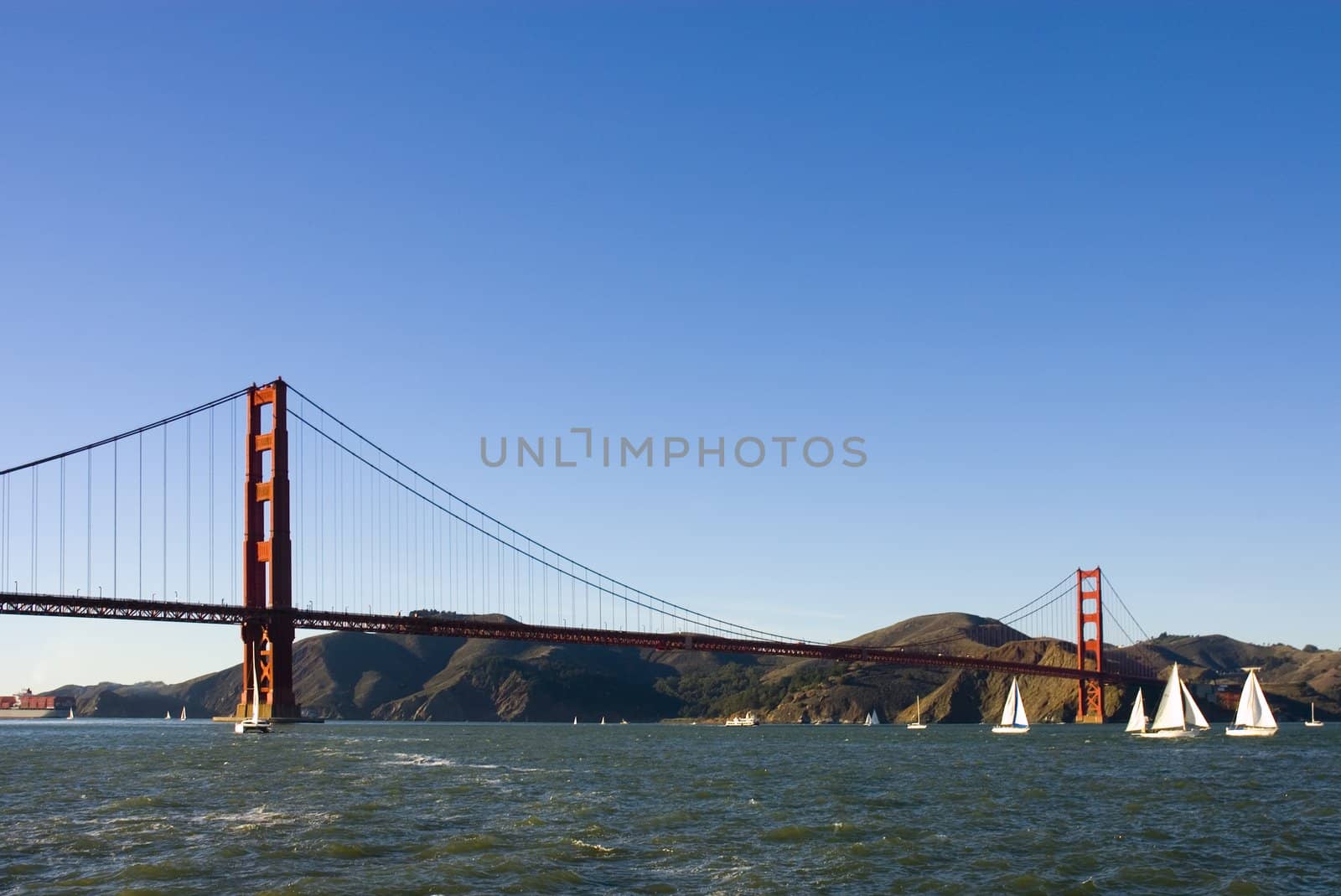 Golden gate bridge from a boat, with sail boats in the bay