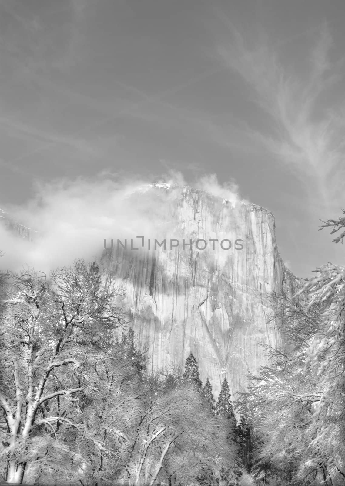 Black and white of El Capitan with small whispy clouds in the winter at sunset