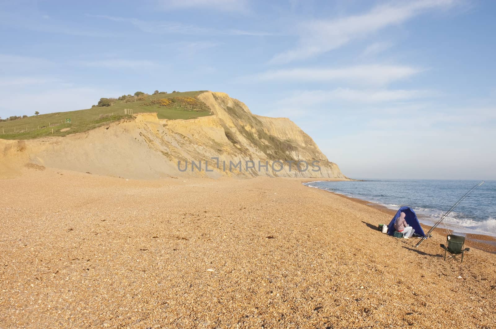 Fishermen alone on Charmouth beach on the Jurassic coast of Dorset at sunset