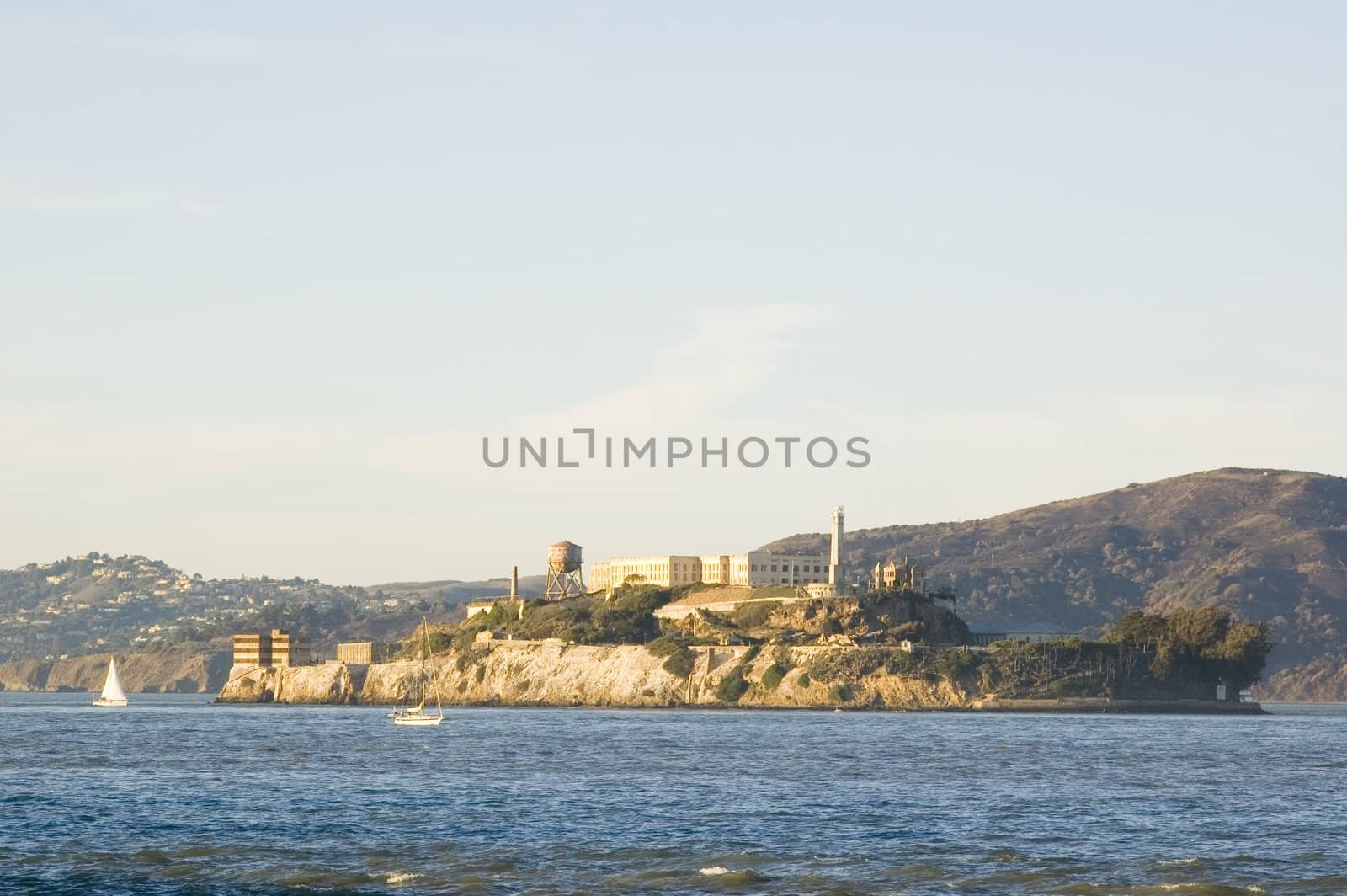 Alcatraz island at sunset, with sail boats in the bay