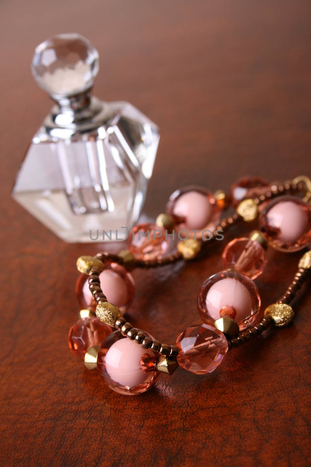 Beaded Jewelery on a brown surface with a glass bottle