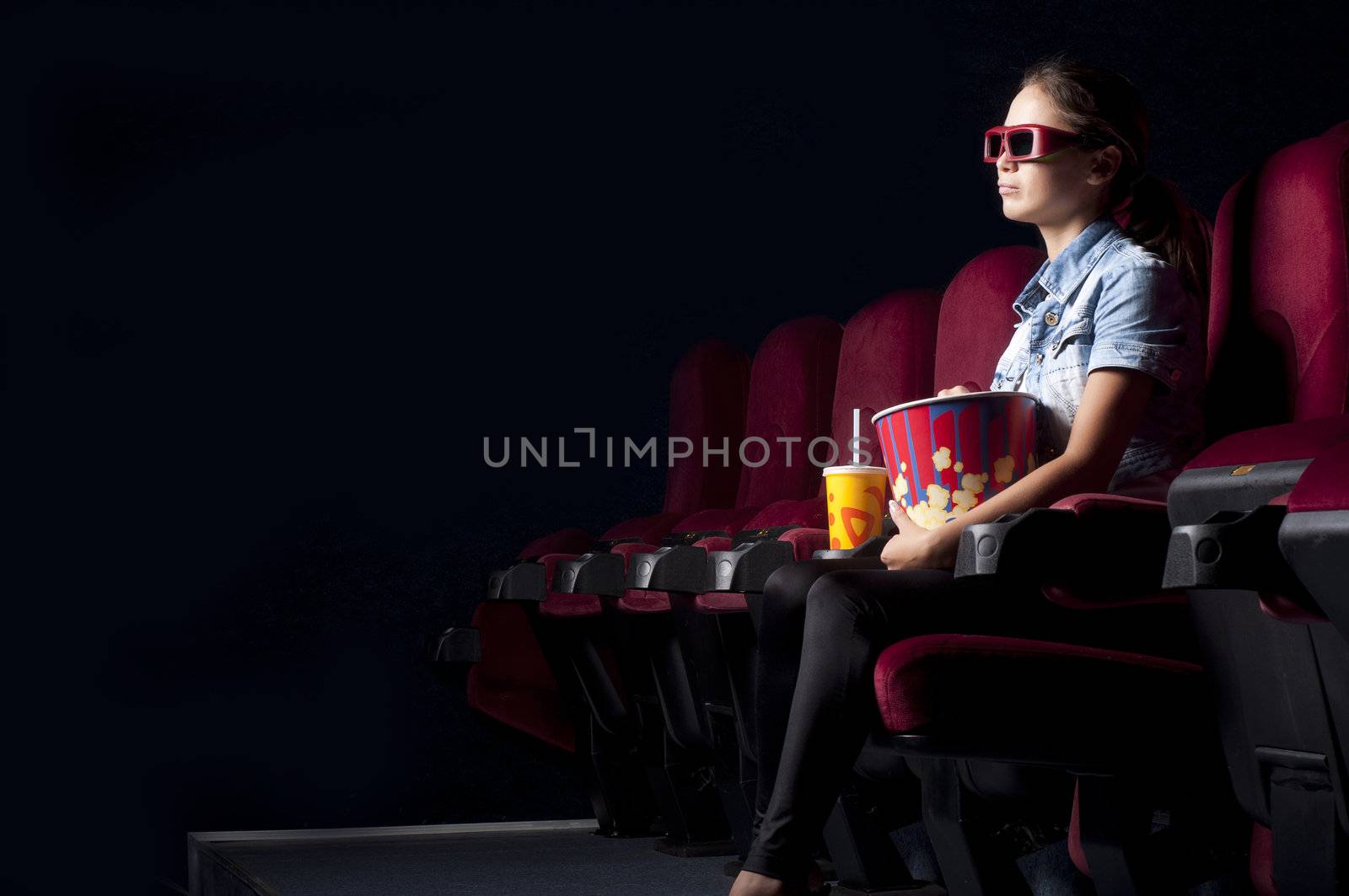 young woman sitting alone in the cinema and watching a movie