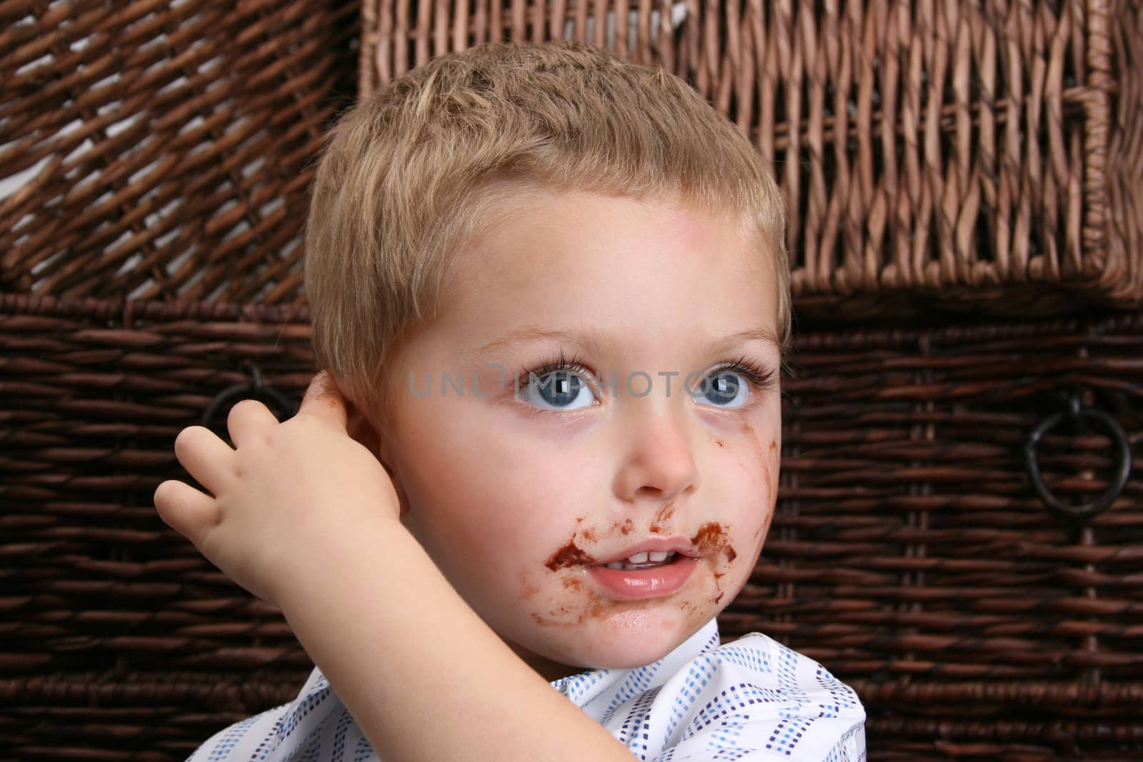 Beautiful blond boy with blue eyes and a dirty mouth, pointing at his ear