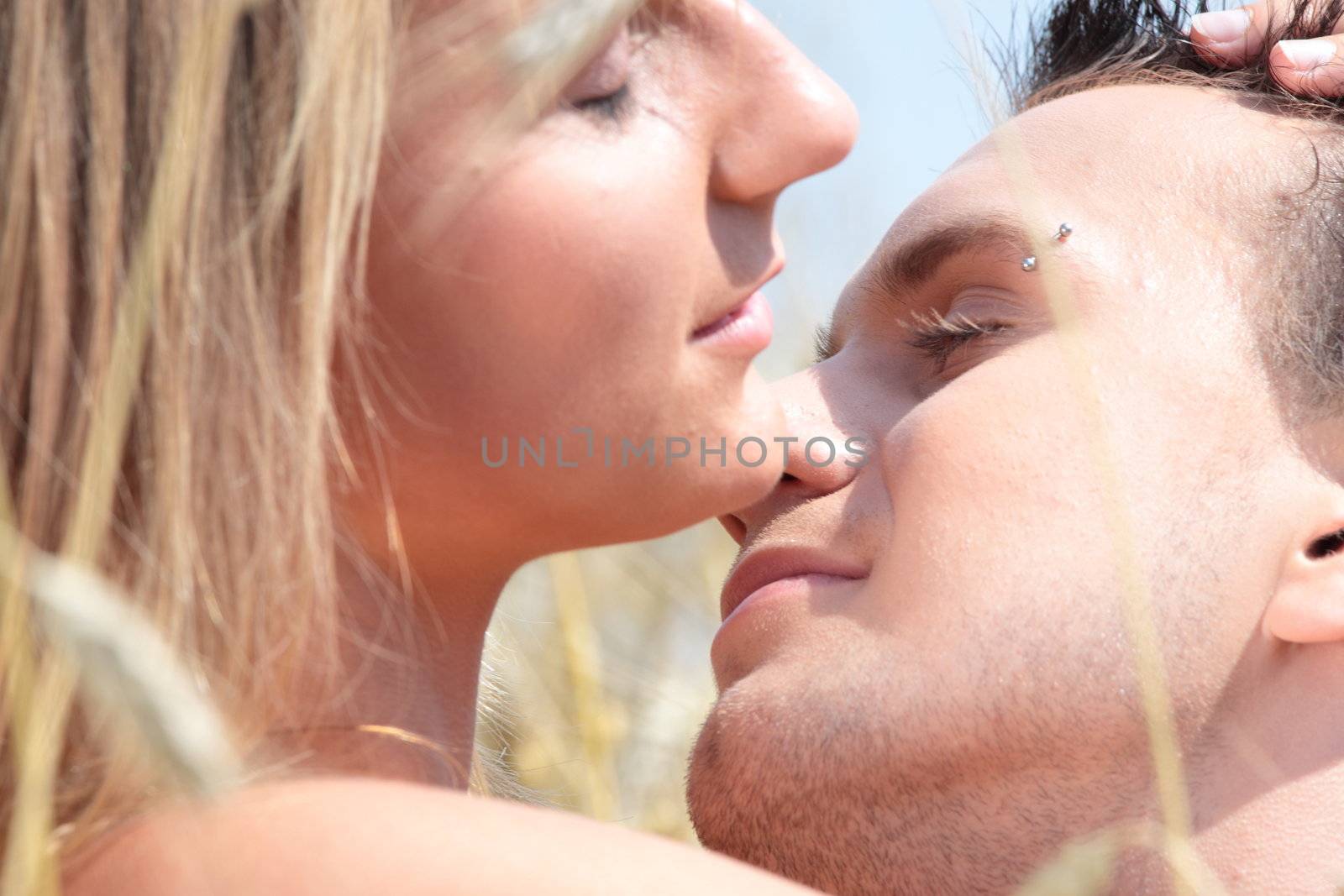A beautiful couple sitting an kissing in wheat field