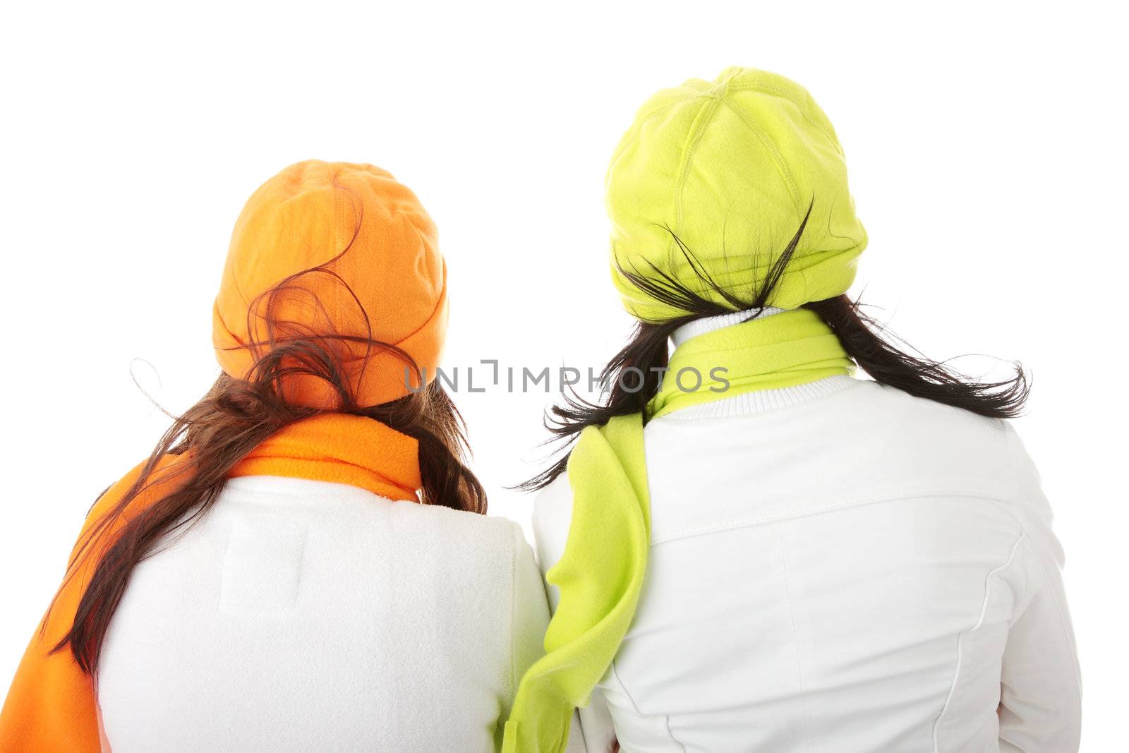 Two girlfriends in winter jackets and hats isolated