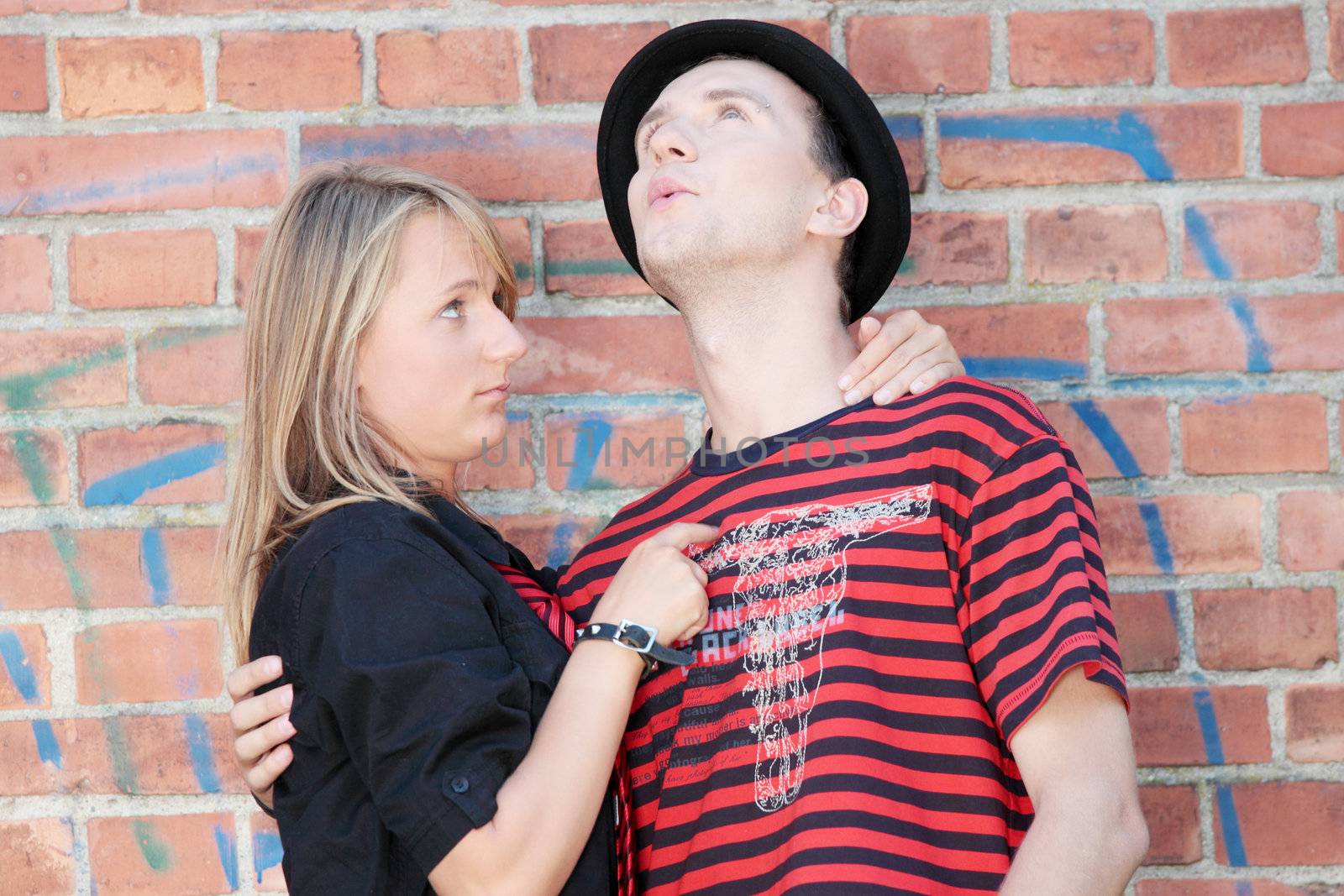 Young punk couple against brick wall