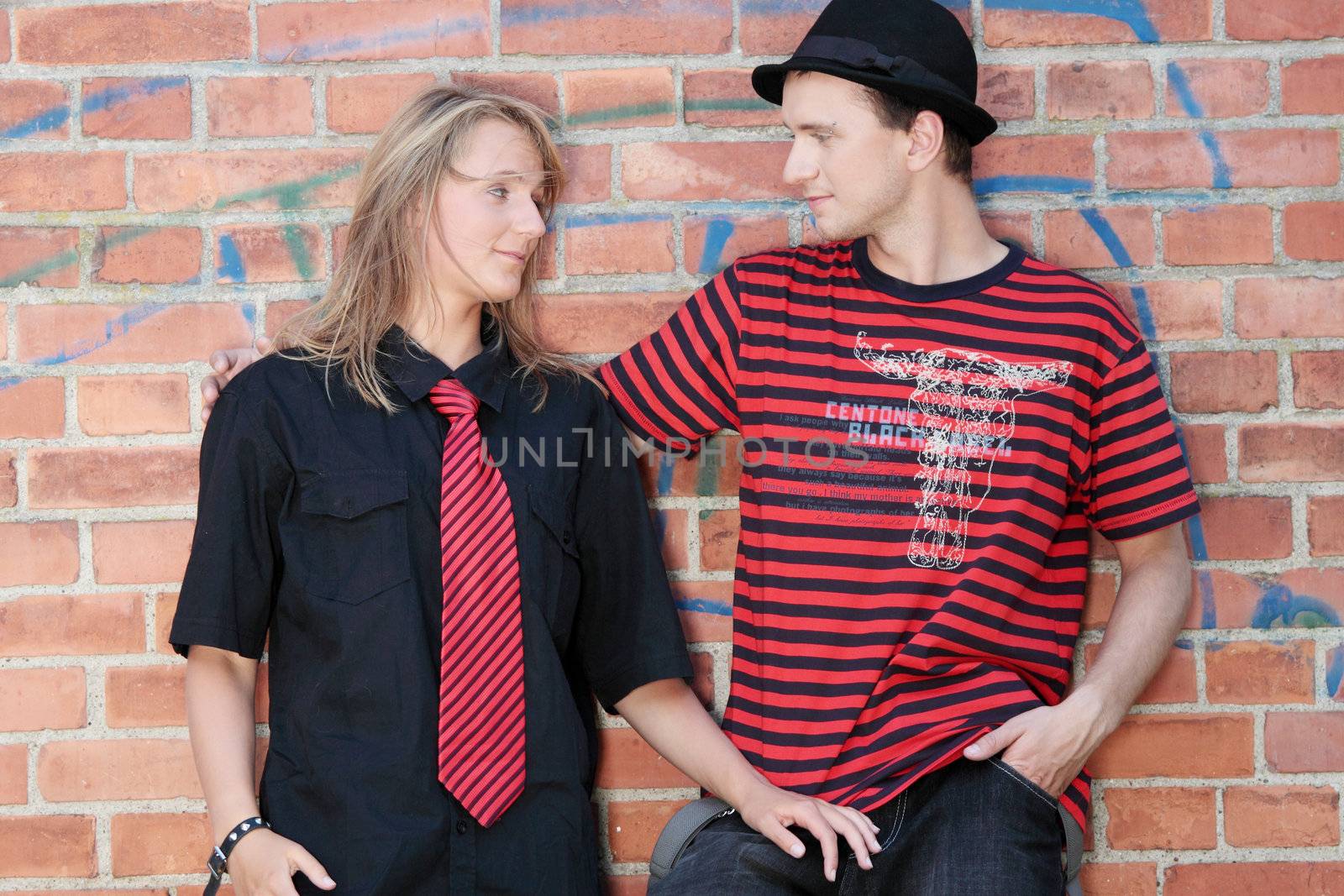 Young punk couple against brick wall