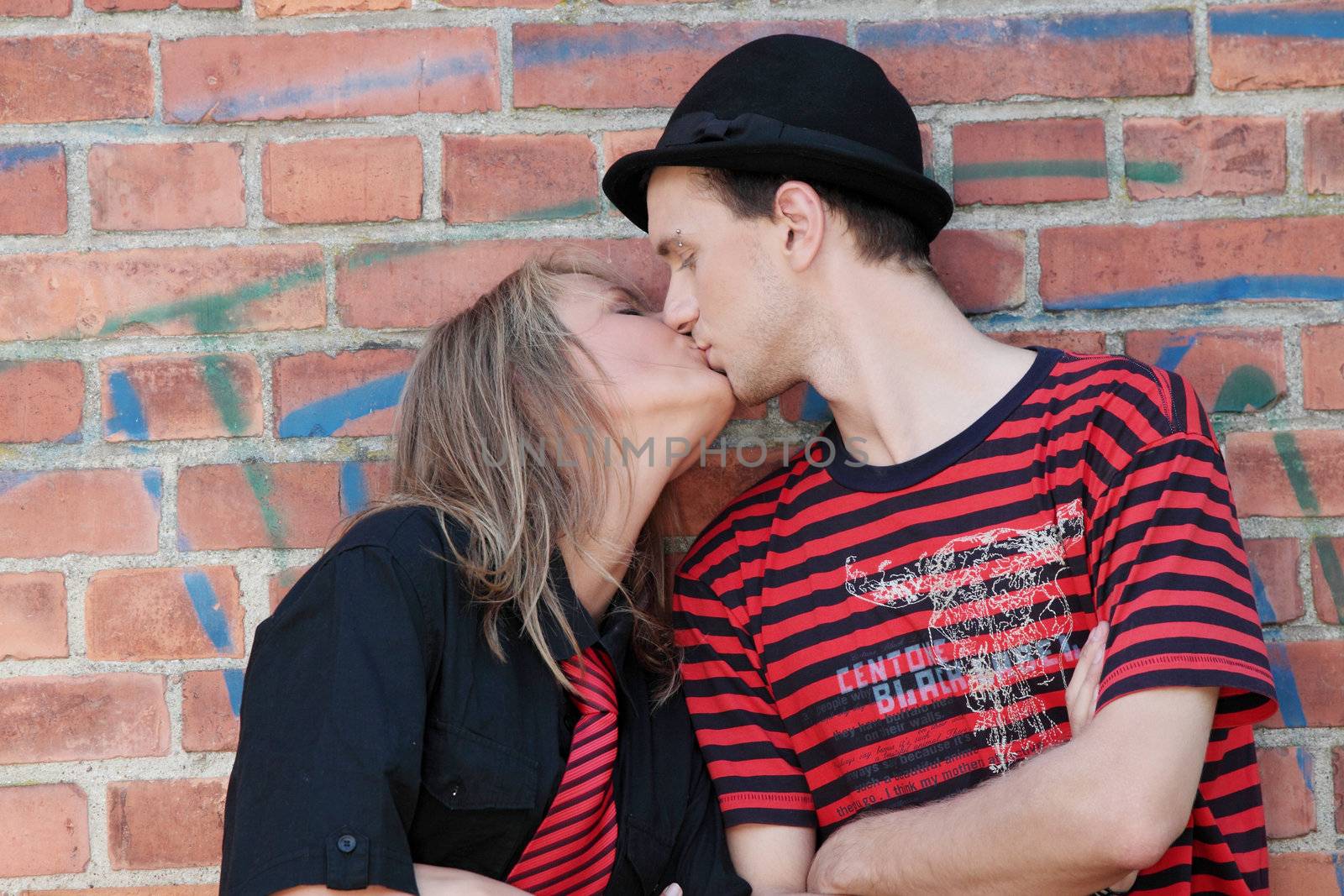 Young punk couple against brick wall