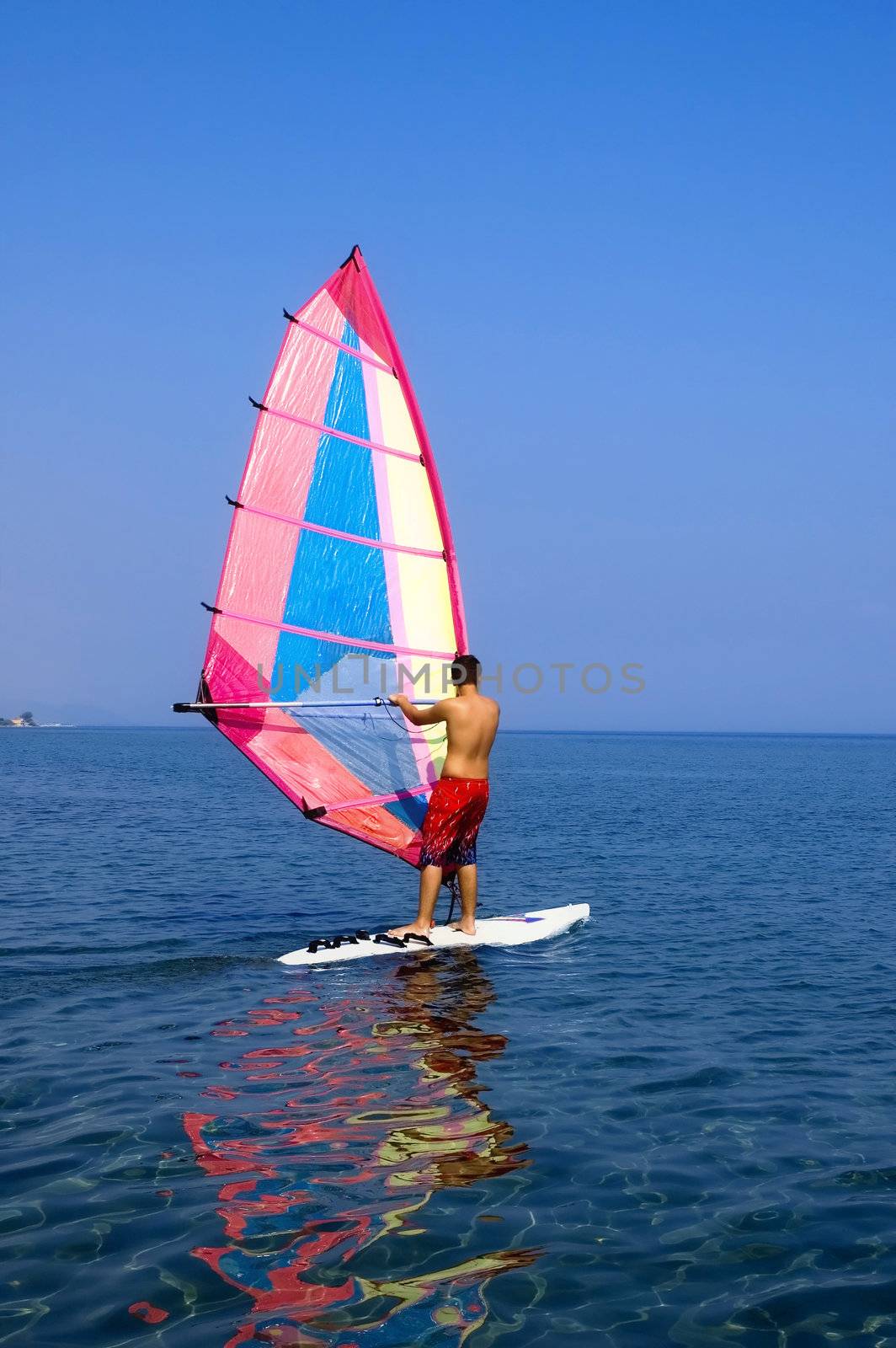 A teenage surfer surfing in Mediterranean sea on a not very windy day