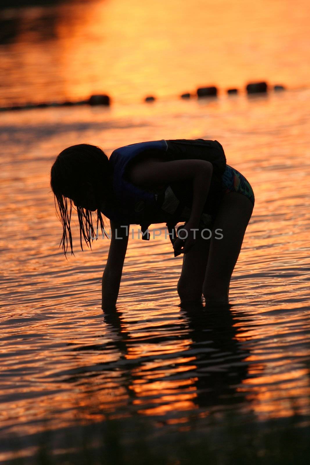 Little girl searching for shells at sunset