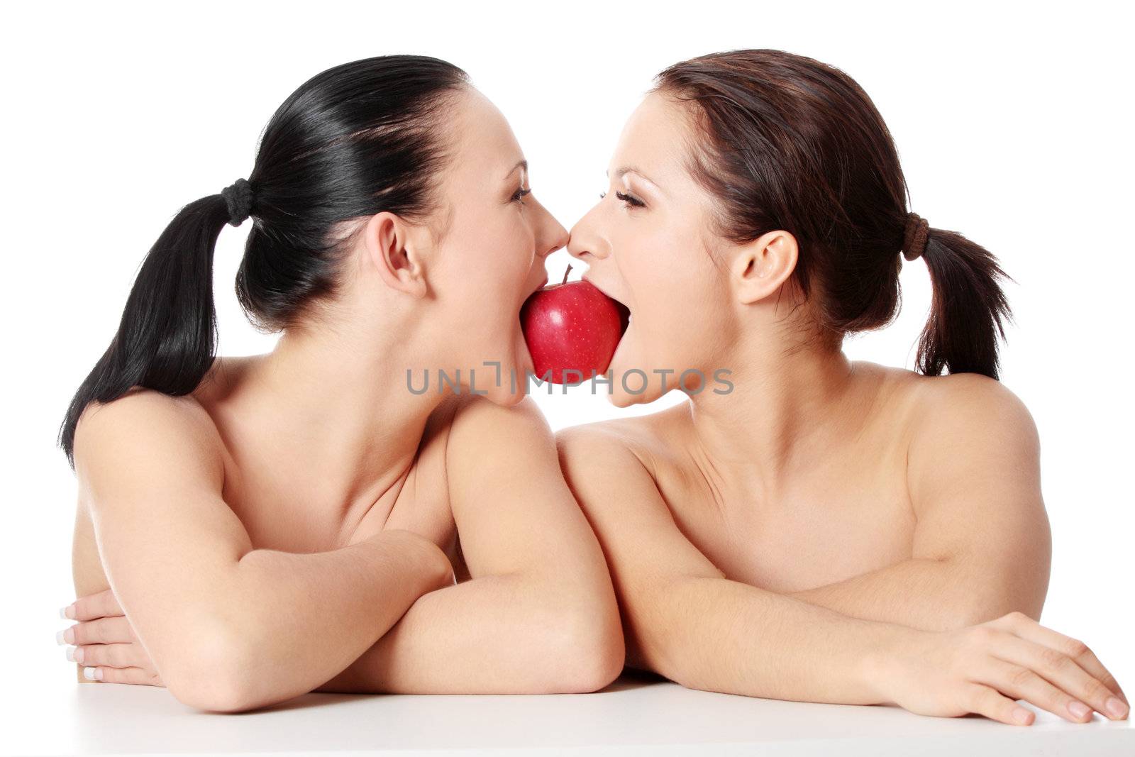 Two young woman biting an apple, isolated on white