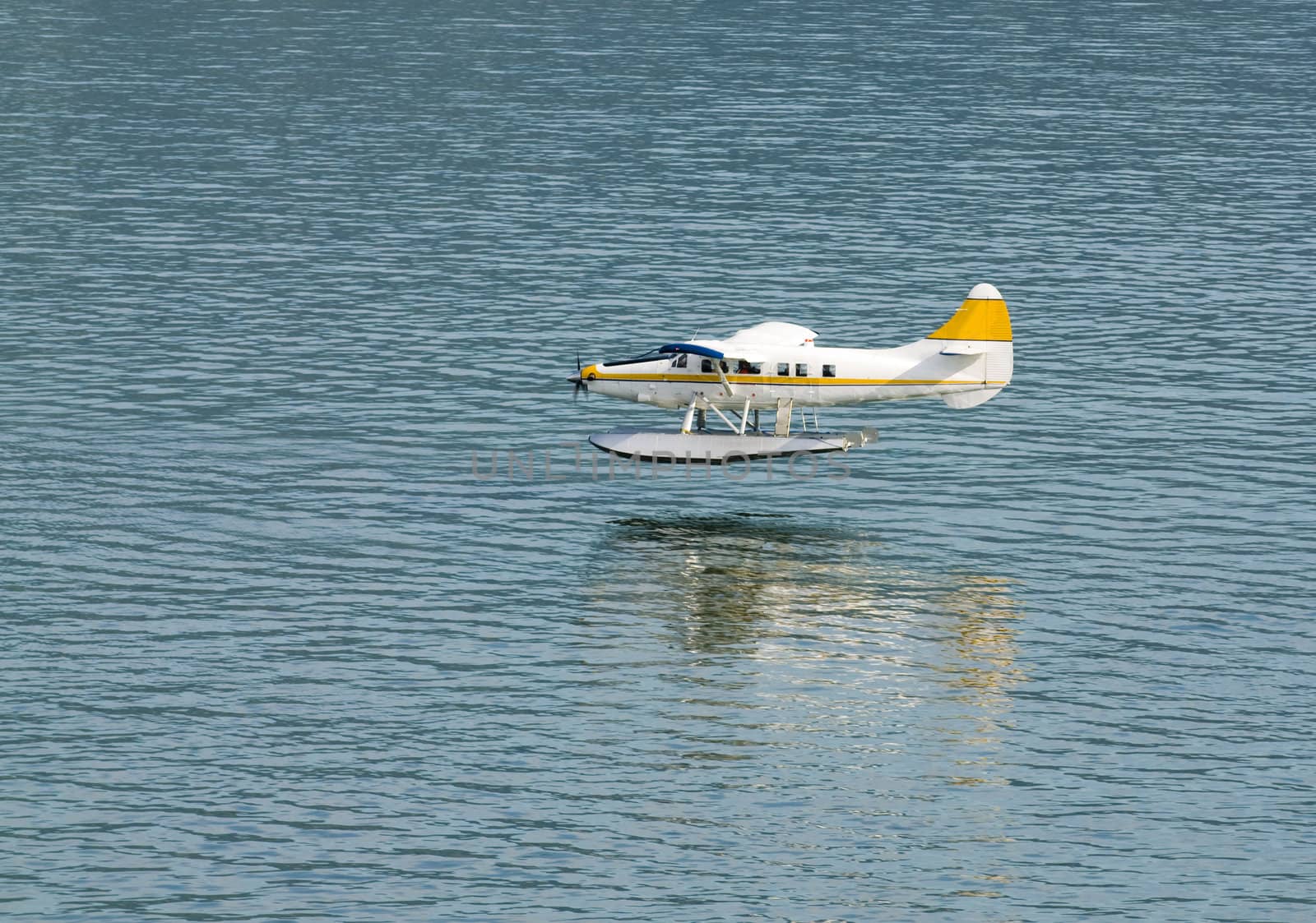 single engined seaplane coming into land with a reflection just prior to touch down