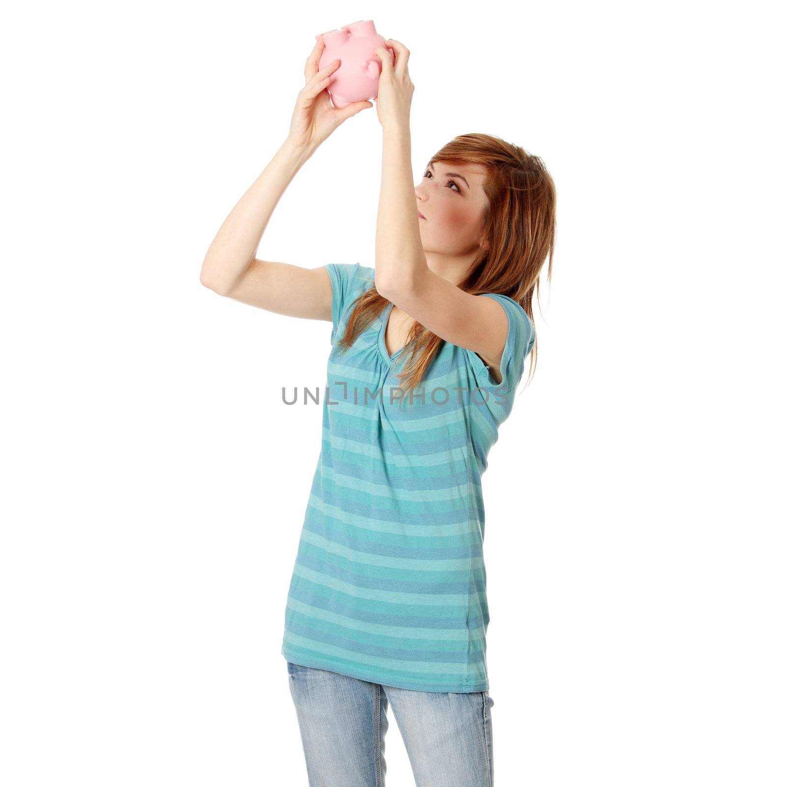 Young woman trying to get money from her piggy bank, isolated on white background
