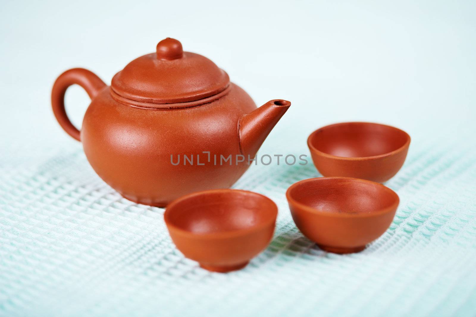 Ceramic teapot and cups on the surface of a blue towel