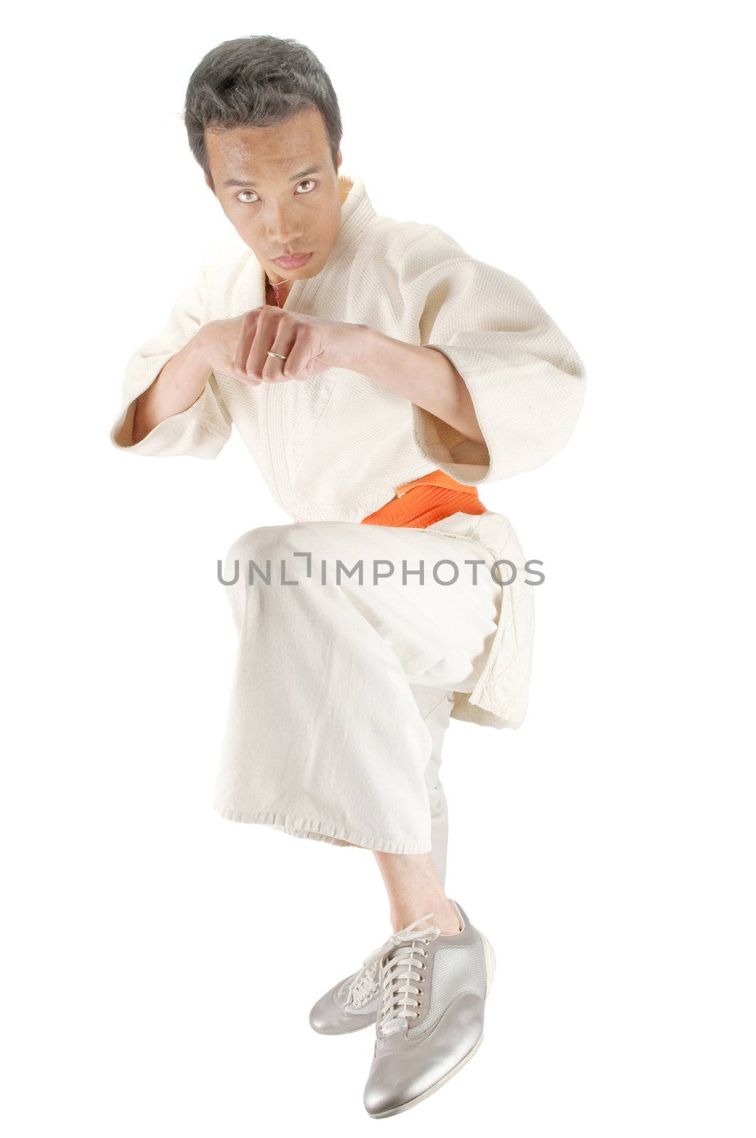 Young asian man in an Aikido, judo, Karate outfit kicking towards the camera isolated on a white background