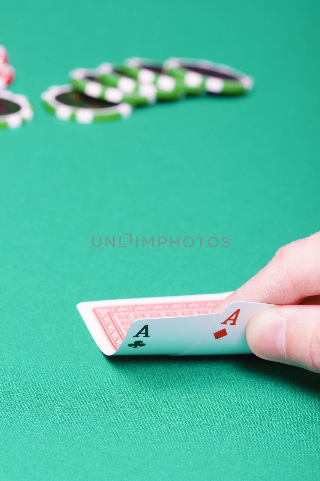 poker player with two aces and chips on a green table
