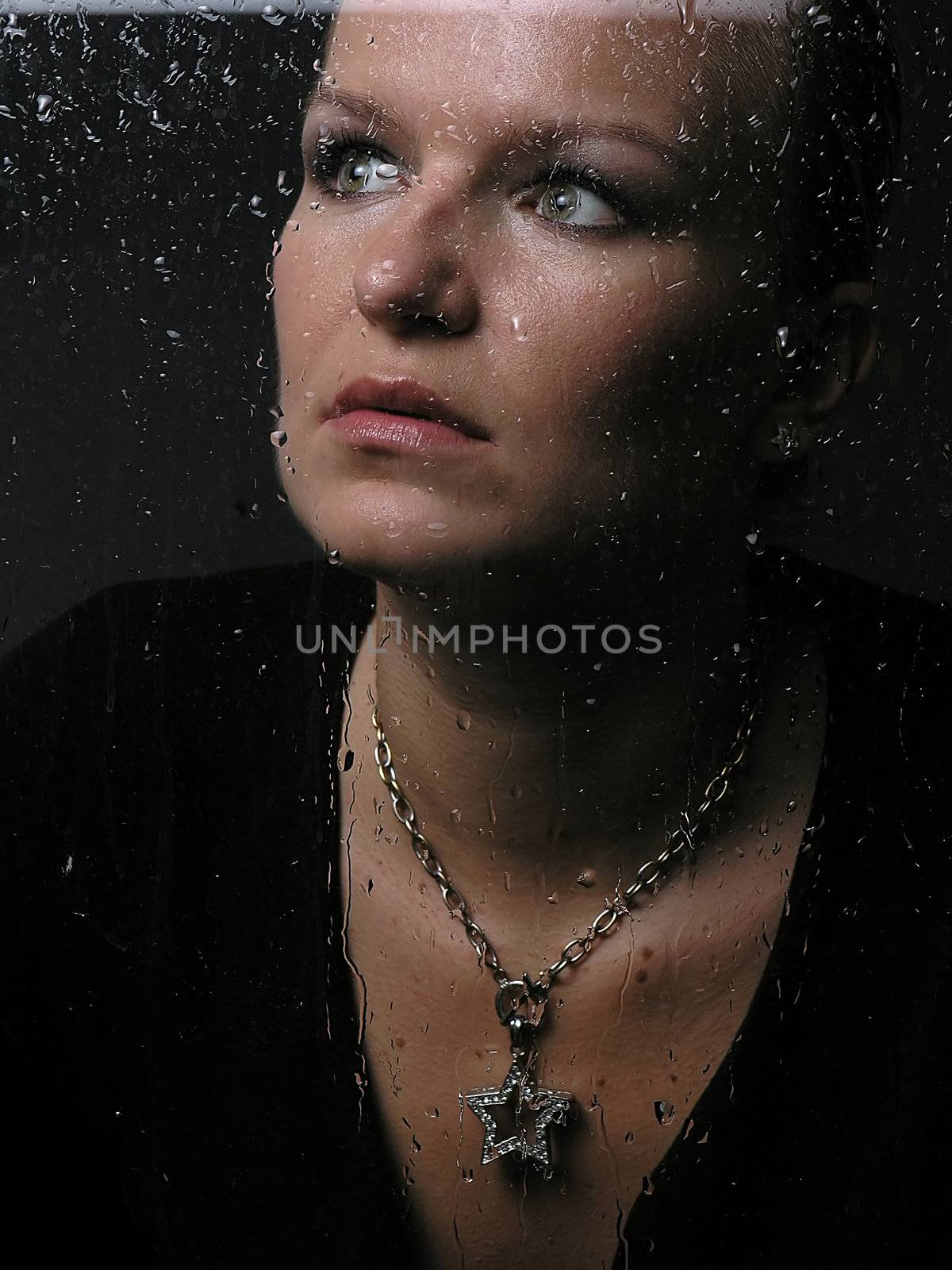 Womans face behind glass with rain drops