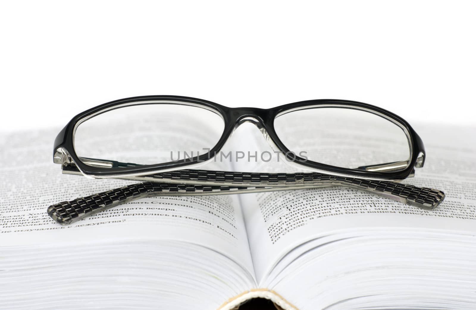 Glasses on open book on white background