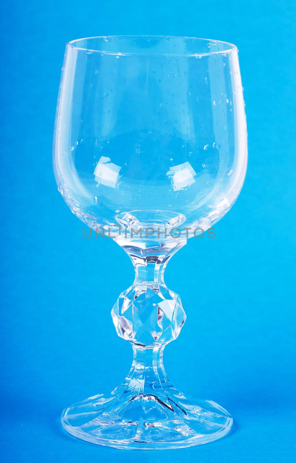 Empty wineglass with drops over blue background