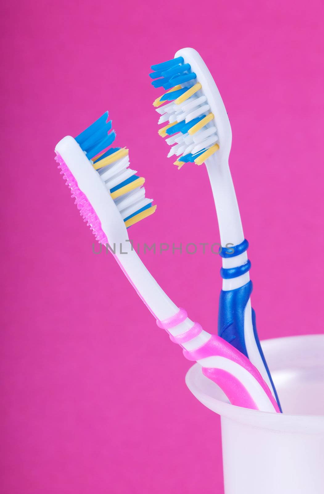 A couple of toothbrushes over pink background