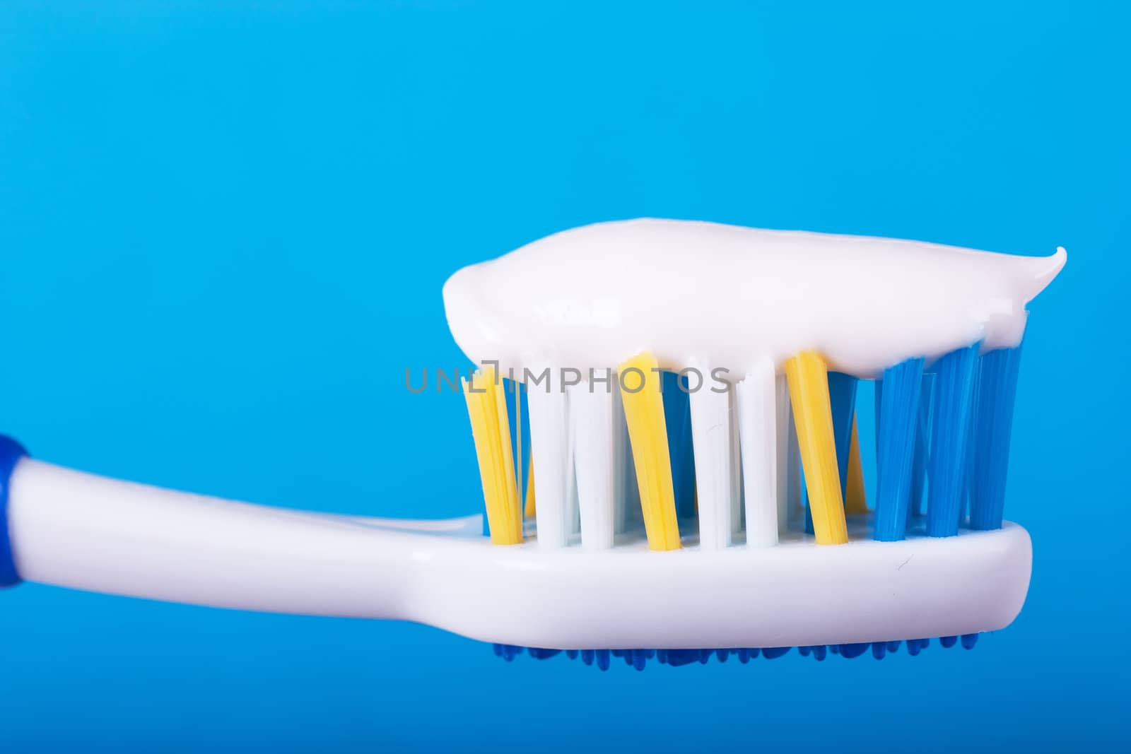 Closeup view of toothbrush with toothpaste over blue background