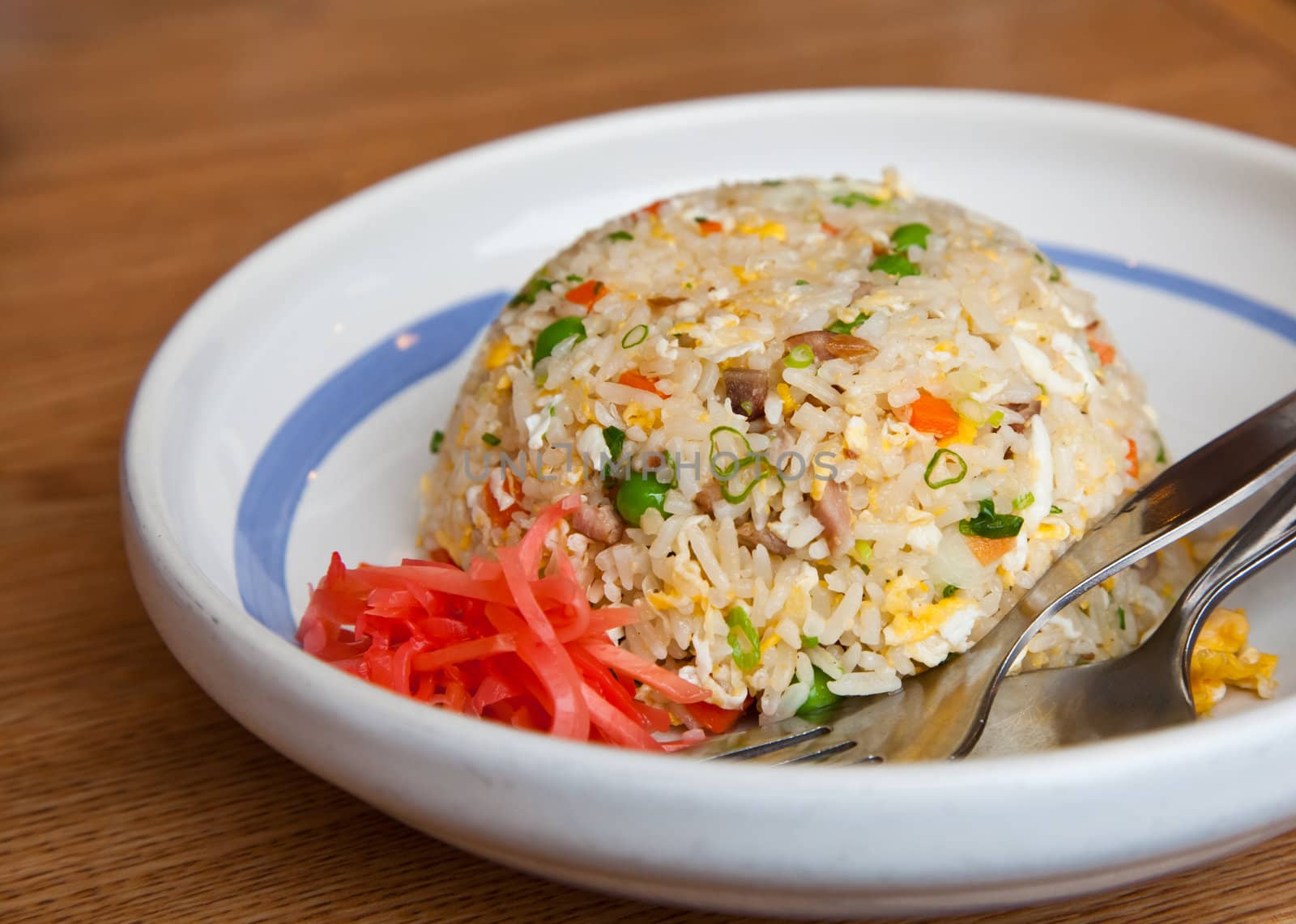 Japanese style fire rice in whith plate on wood table.