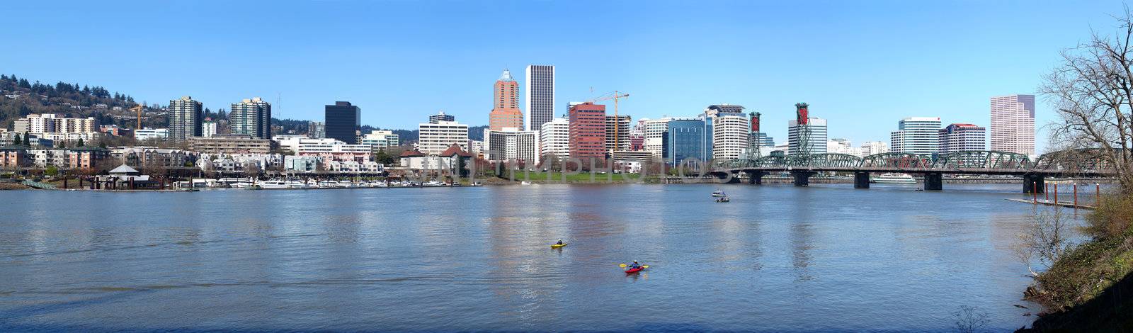 A panoramic view of the city of Portland Oregon and kayaks in the river.