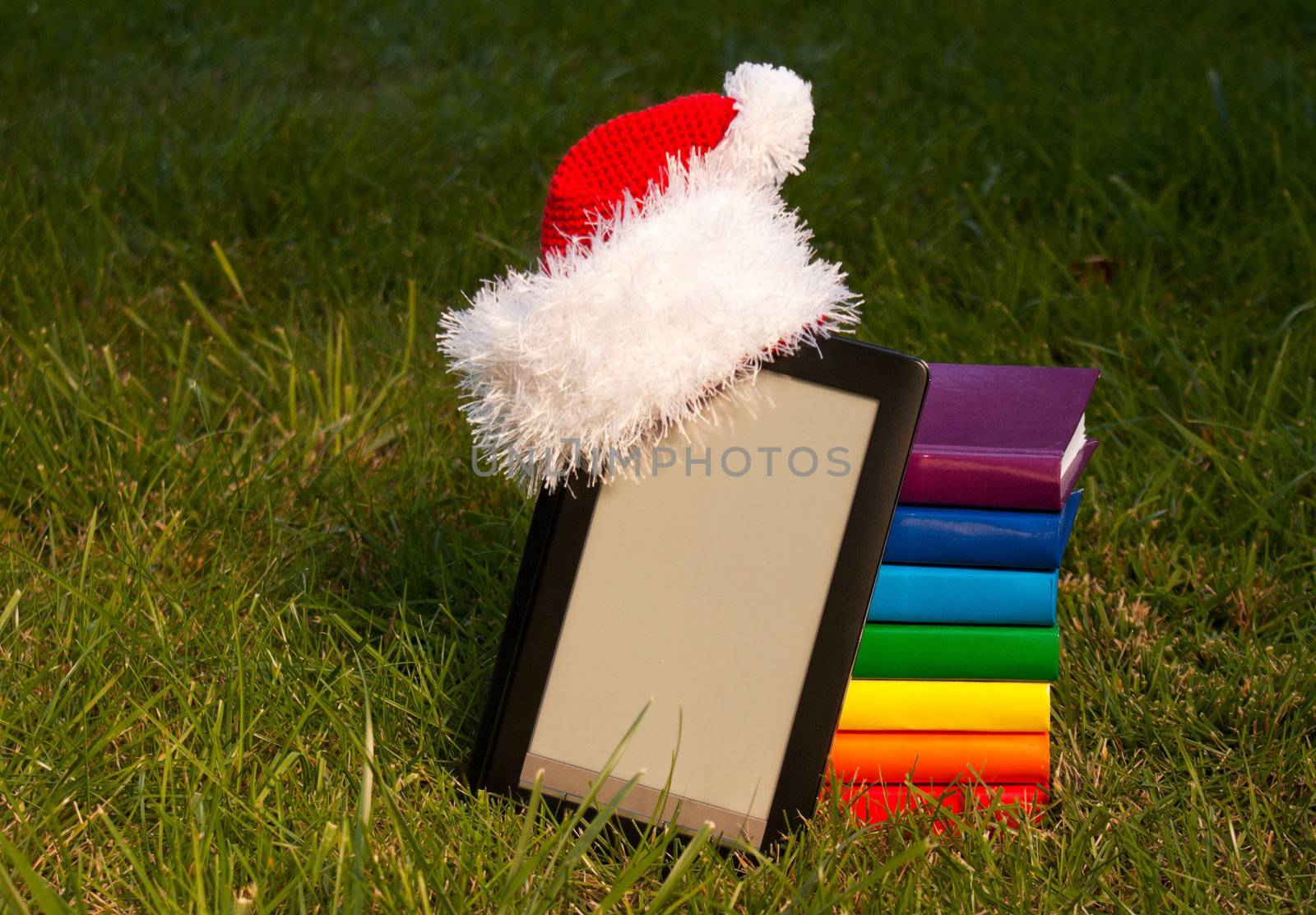 Electronic book reader wearing Santa's hat with stack of books