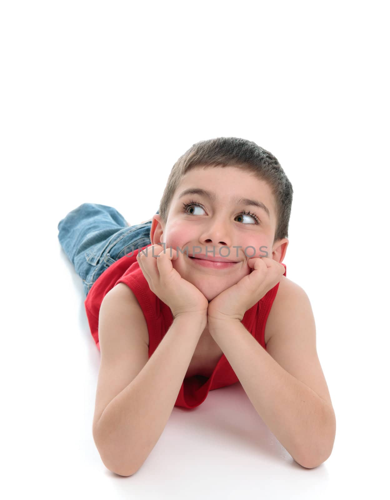 A young boy lying on the floor, smiling and looking sideways.  Suiteable for copy. White background.