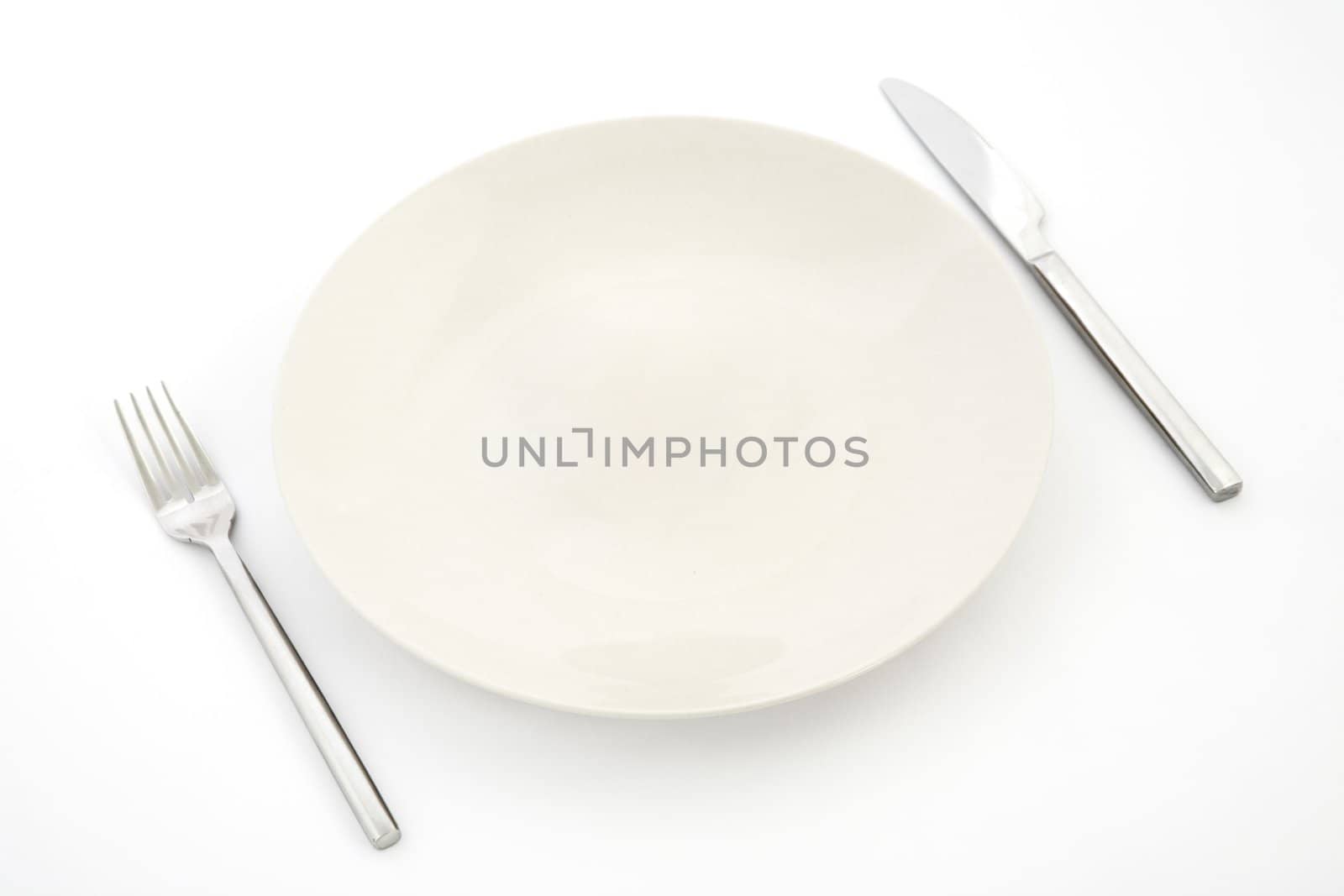 top view of white plate, fork and knife, restaurant tableware