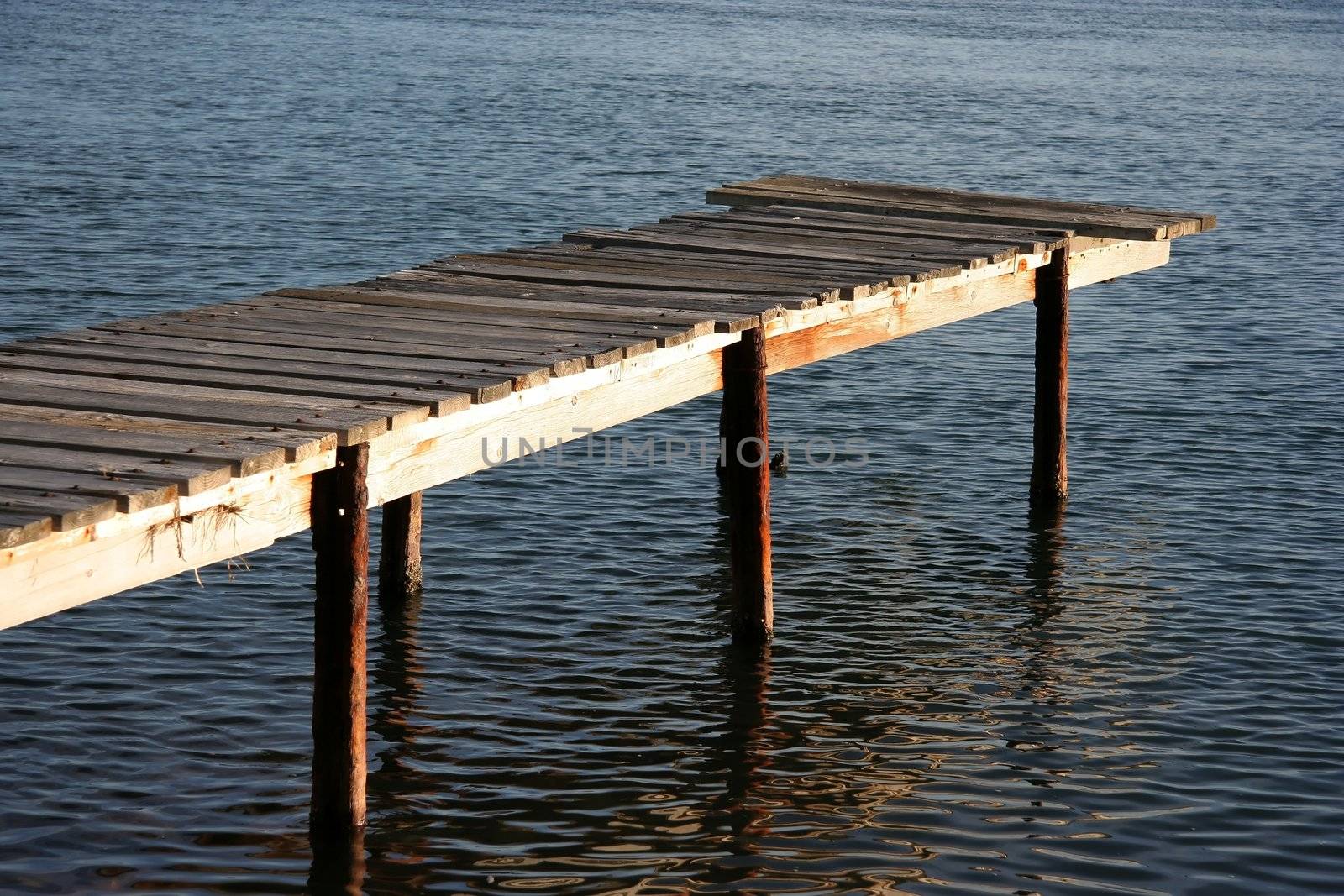 Old wooden jetty with steel supports on a river