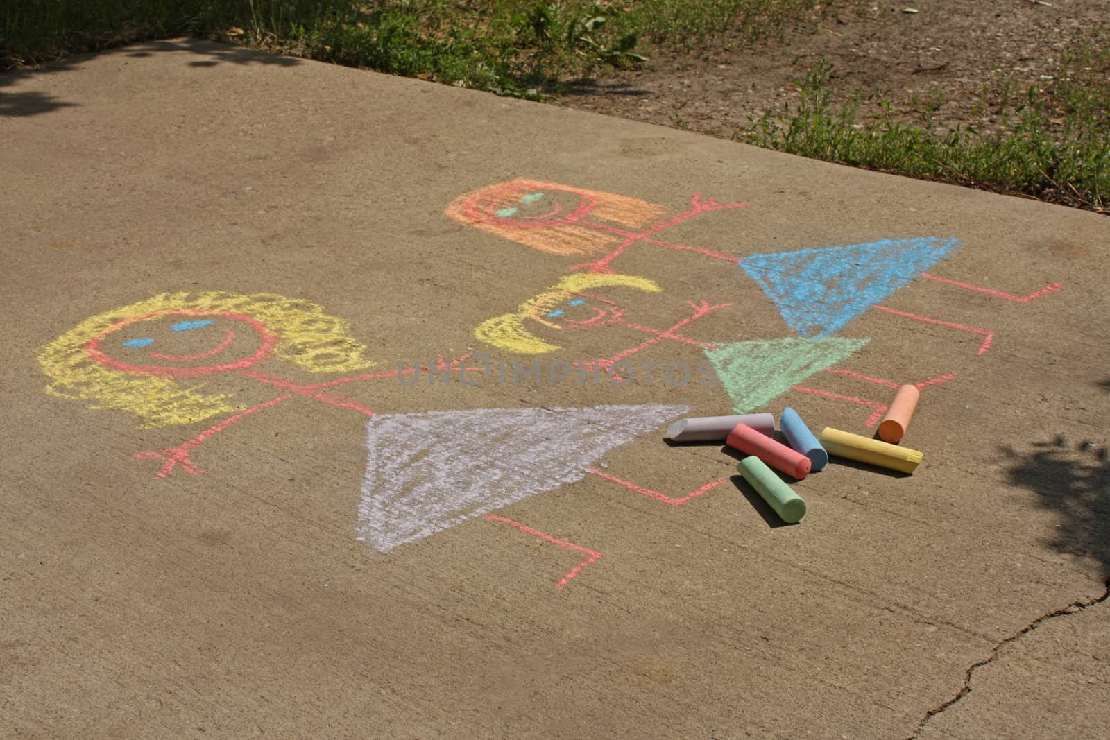 Concept image for gay parenting or gay marriage; a chalk child's drawing on a sidewalk or driveway, of two women and a female child.