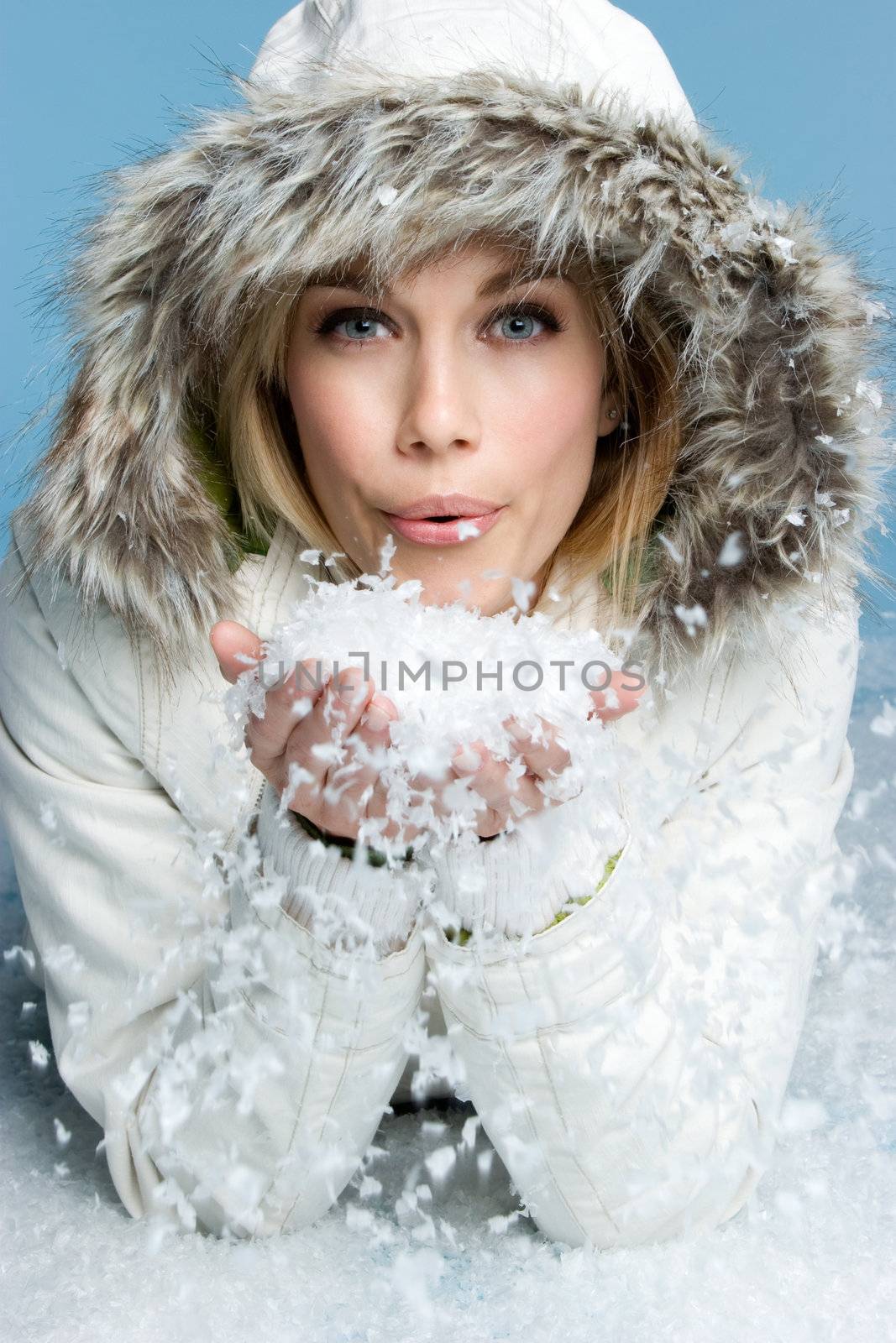 Beautiful winter woman blowing snow