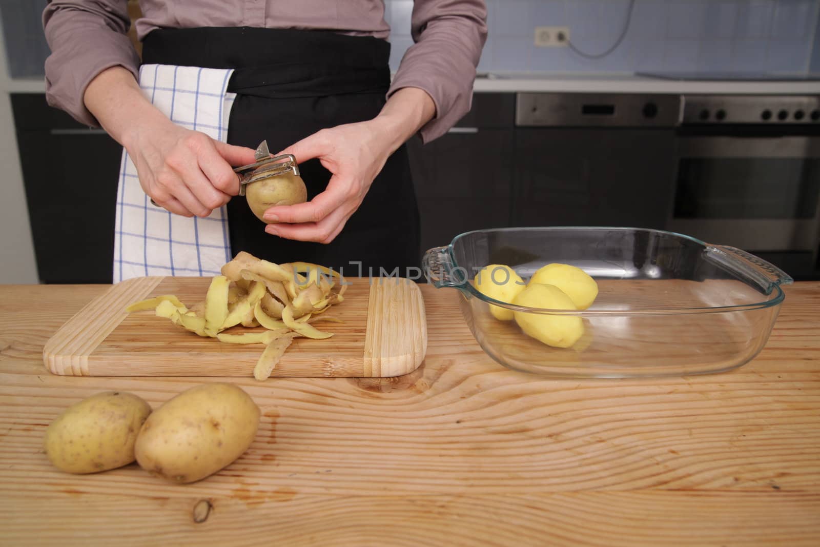 Peeling a potato with peeler in a kitchen